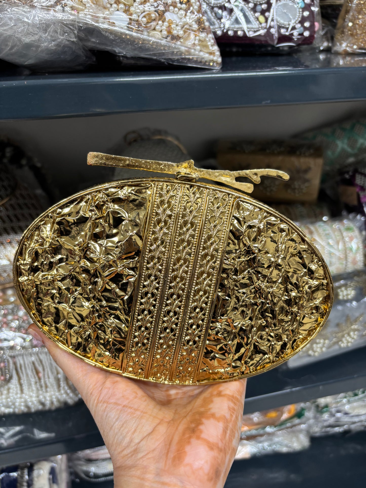 Gold belt buckle held by a hand with a blurred background of shelves.