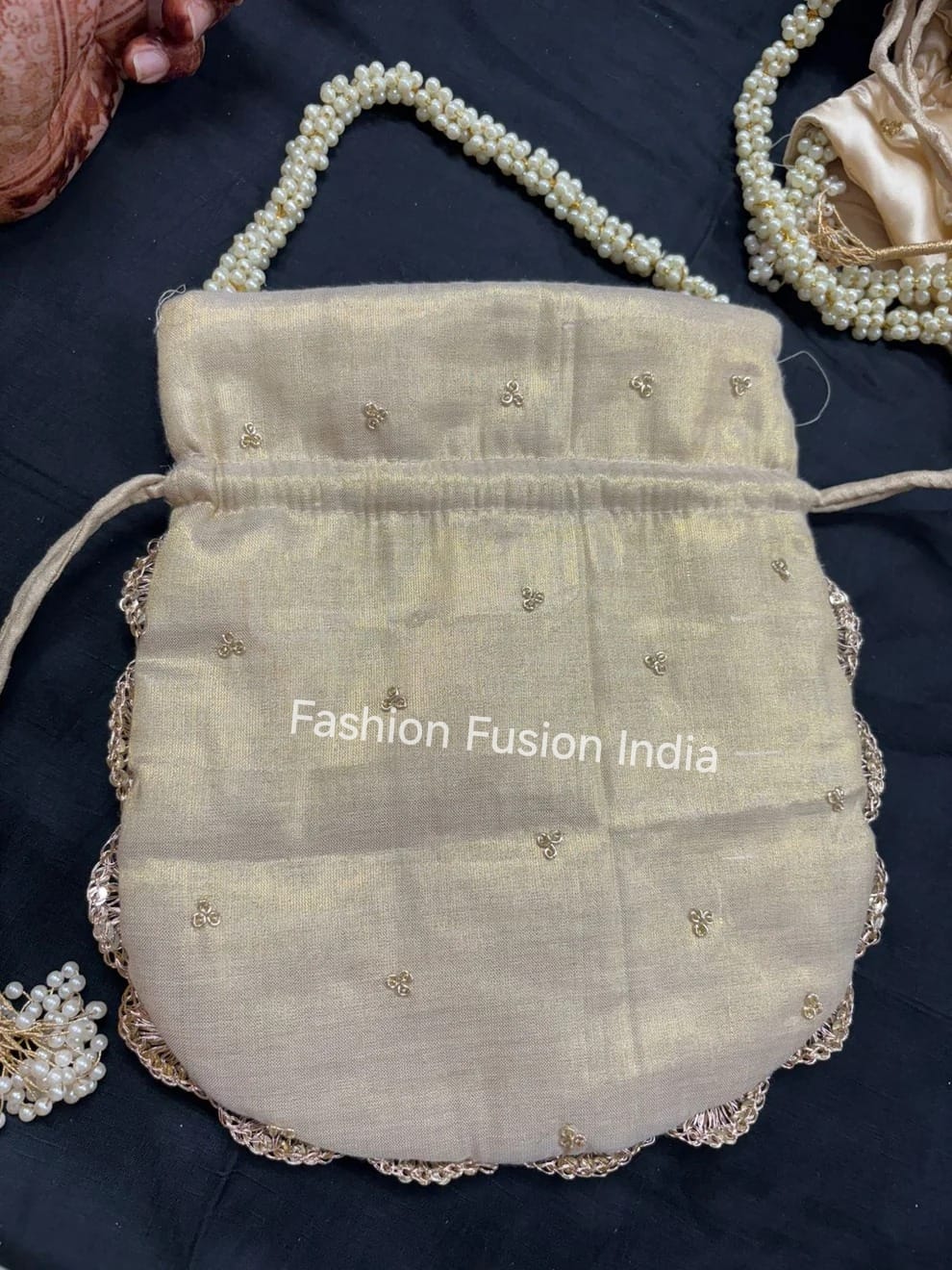Beige handbag with decorative elements on a dark background, featuring 'Fashion Fusion India' branding.