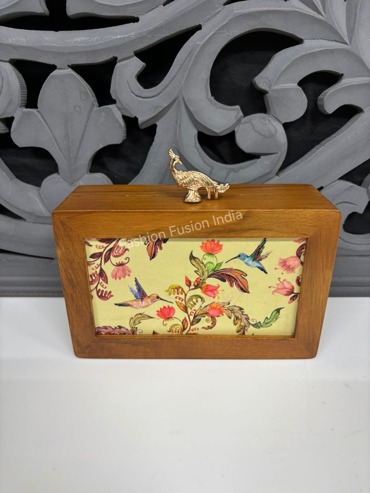 Wooden floral bird print box with a gold peacock handle, displayed against a carved grey backdrop.