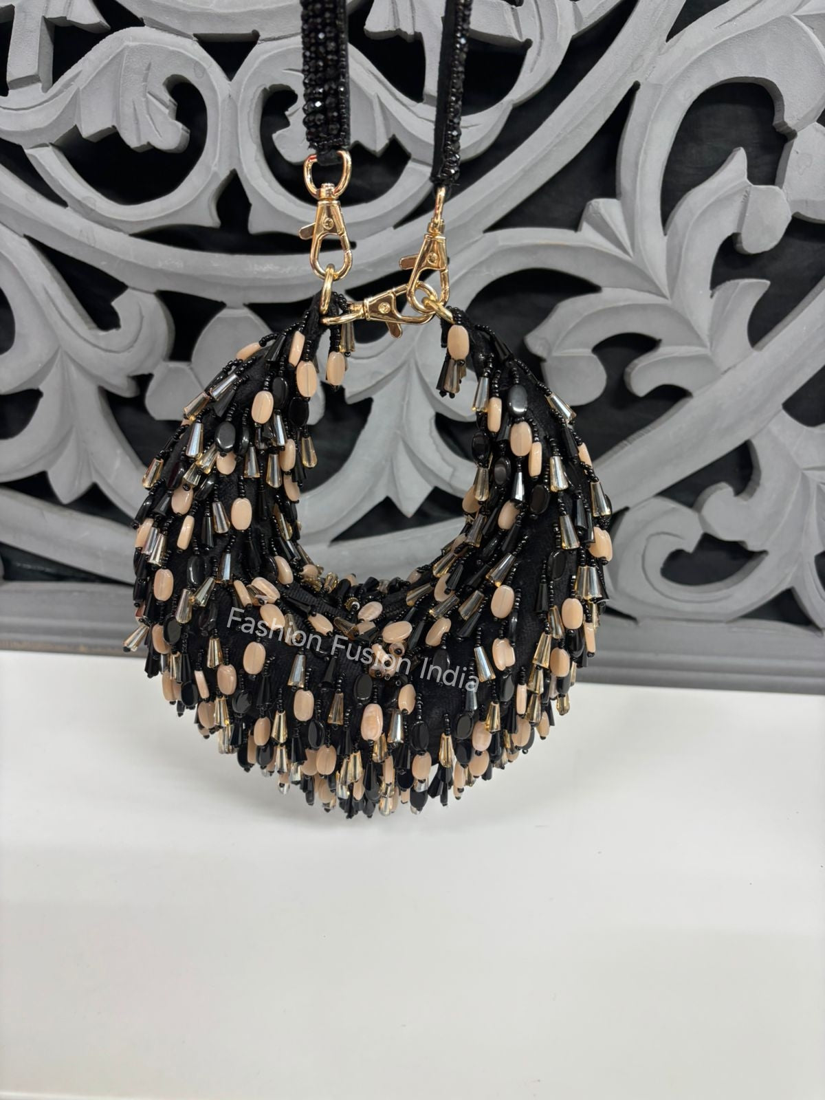 Black and beige beaded handbag with gold accents on a decorative white background