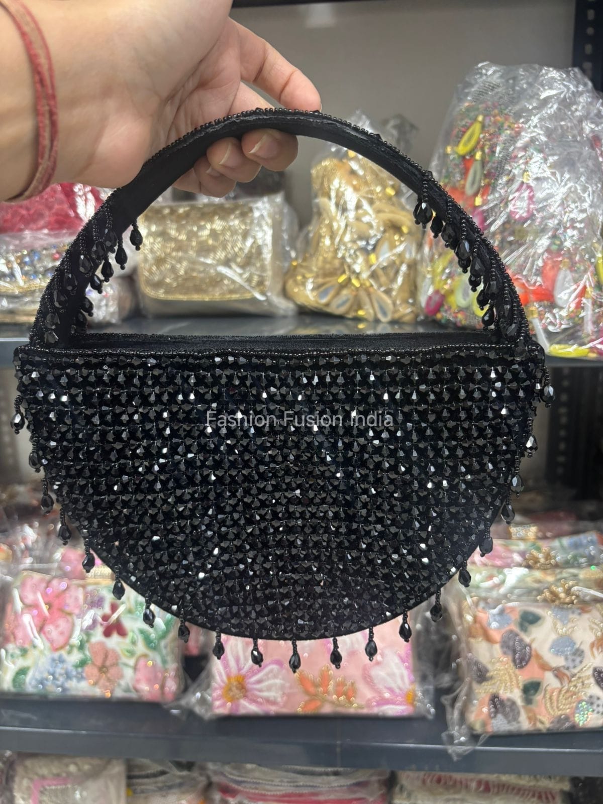 Black beaded handbag held by a hand with a blurred background