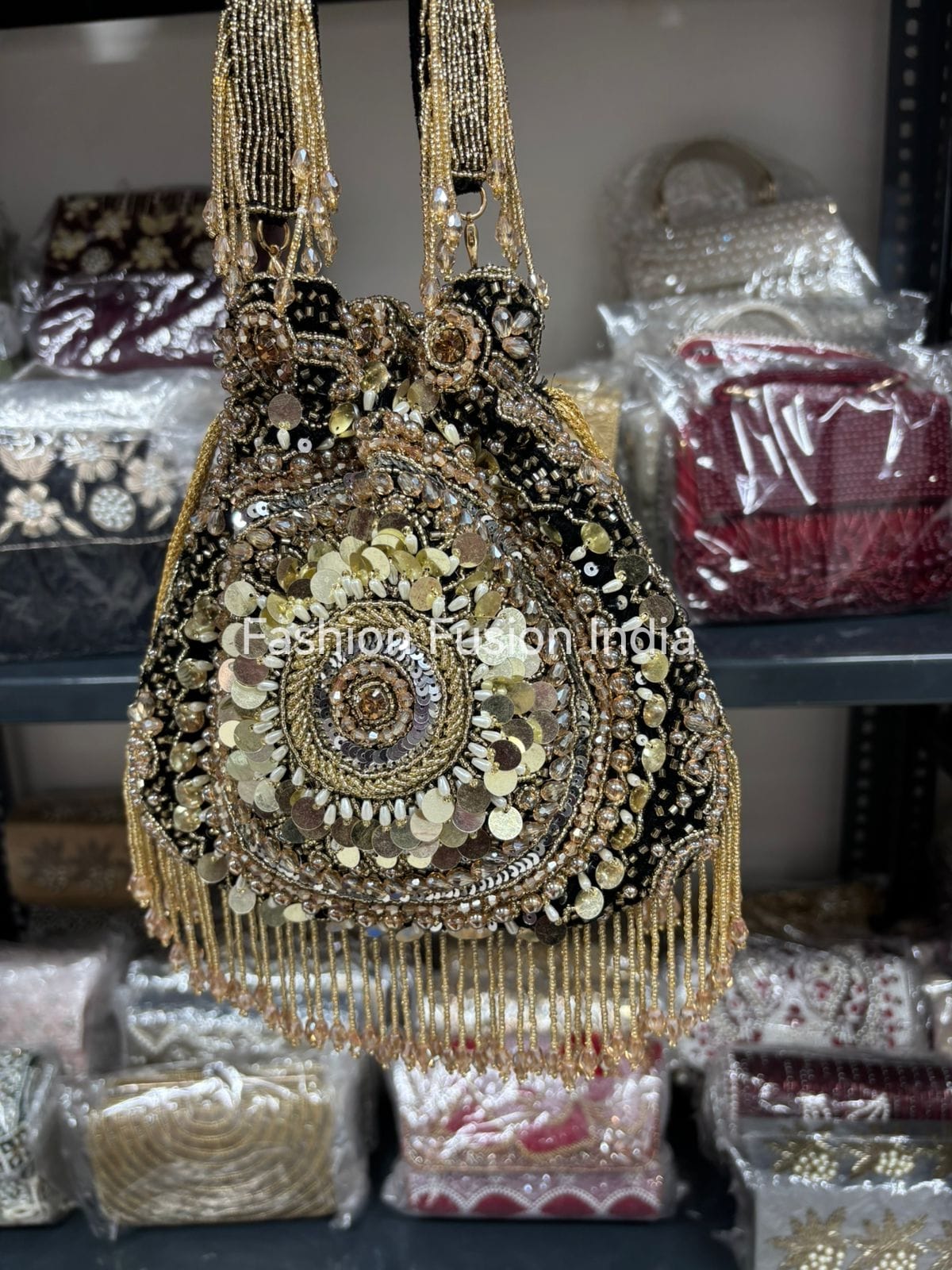 Decorative handbag with gold and black embellishments on a shelf with other bags.