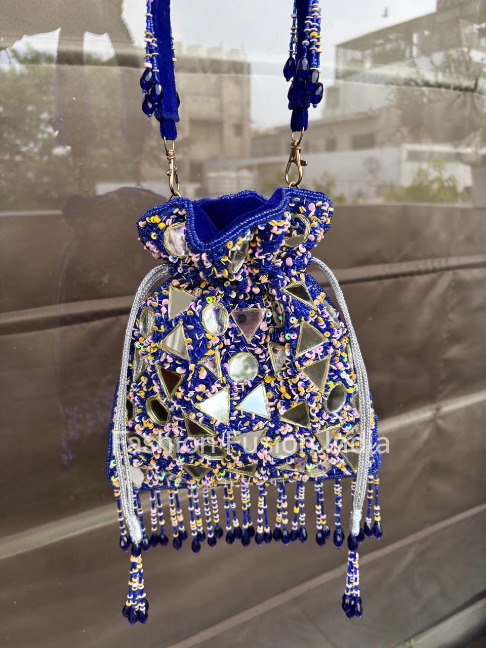 Decorative handbag with blue and silver beads on a reflective surface