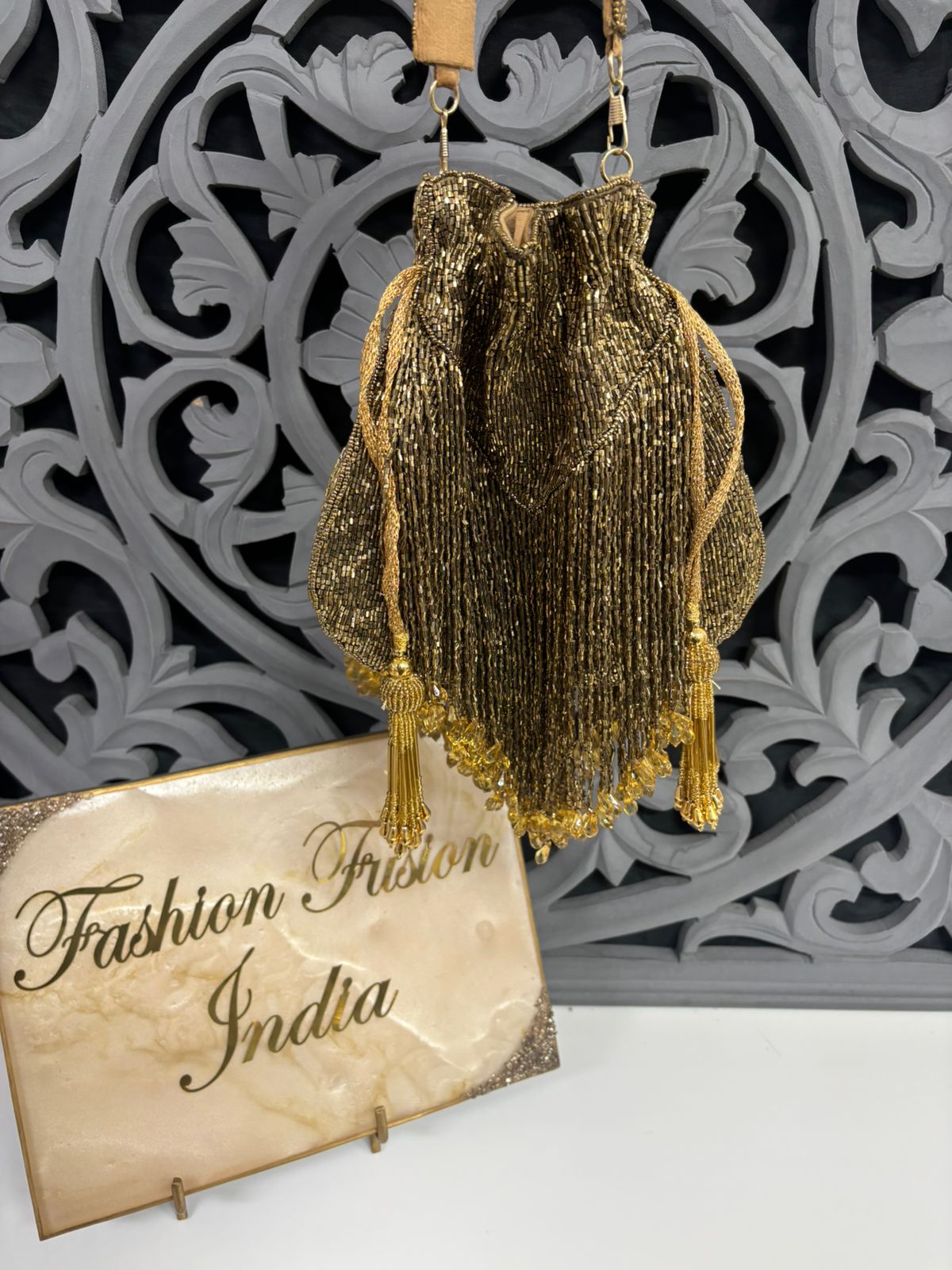 Decorative gold beaded bag with 'Fashion Fusion India' sign in the background