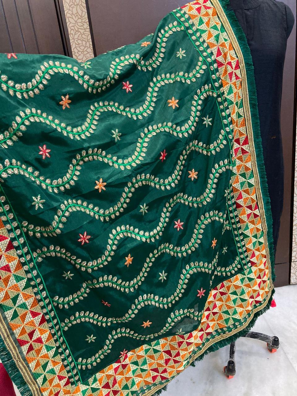 Green embroidered fabric with colorful patterns on a plain background