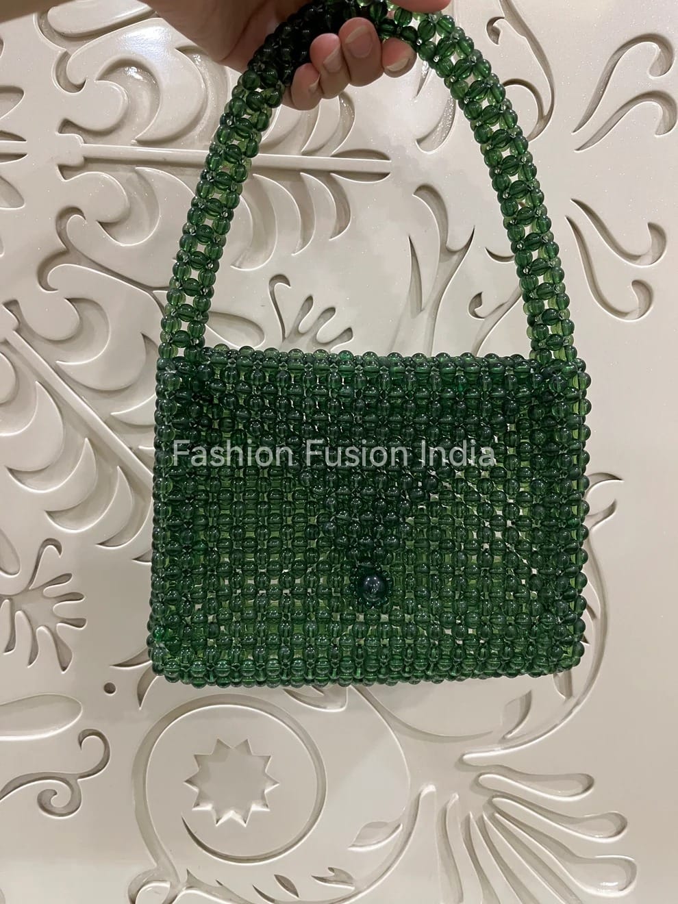 Dark Green beaded handbag held by a hand against an ornate white background with 'Fashion Fusion India' branding.