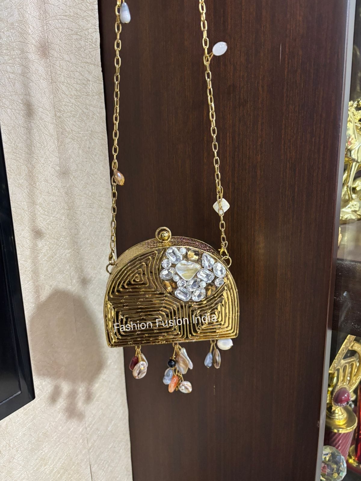 Decorative gold pendant with crystals and beads on a chain against a wooden background