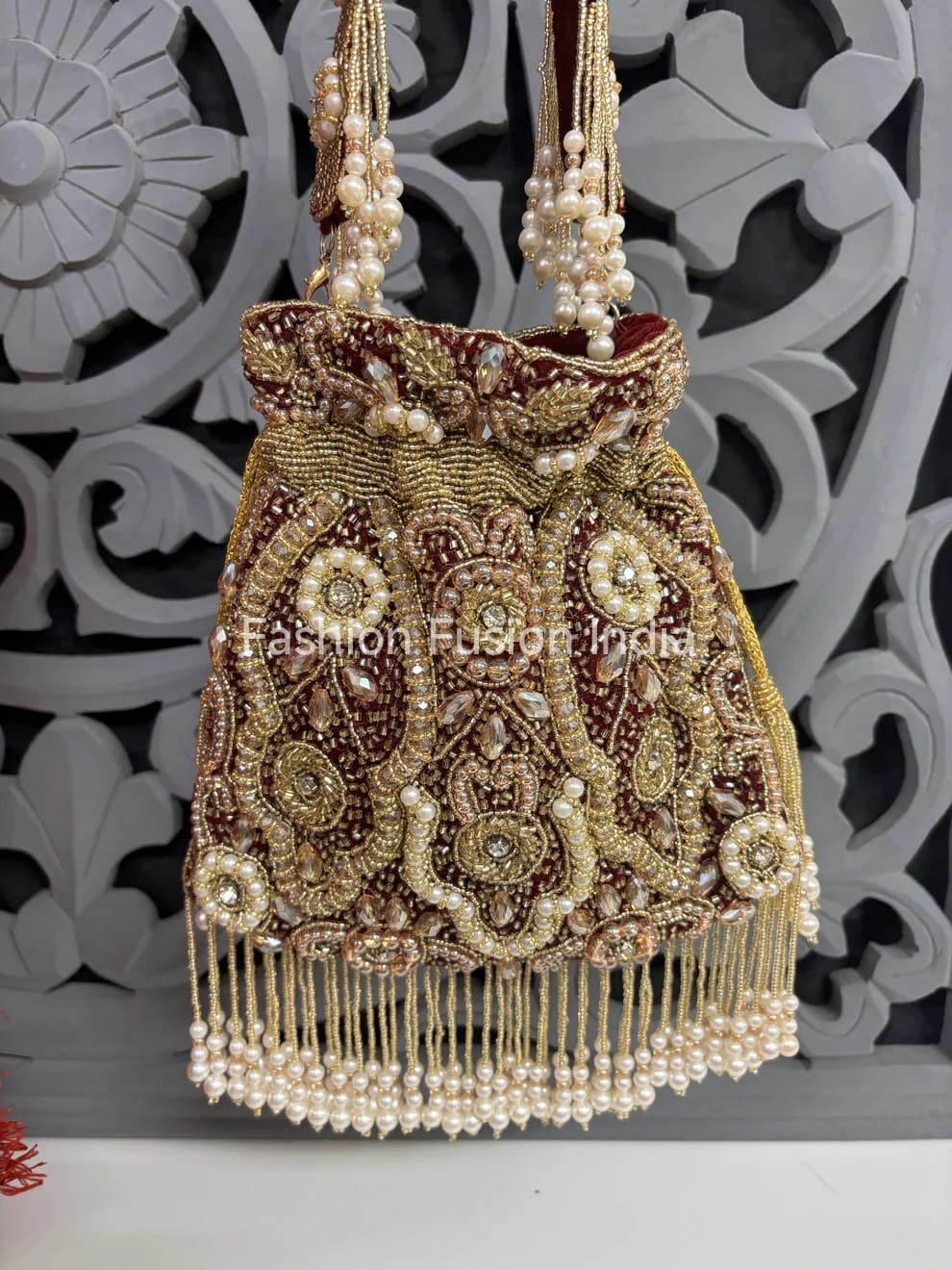 Decorative handbag with intricate designs and pearl embellishments against a decorative white and black background.