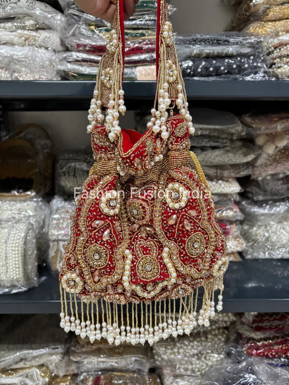 Decorative handbag with intricate designs and pearl details held against a blurred background.