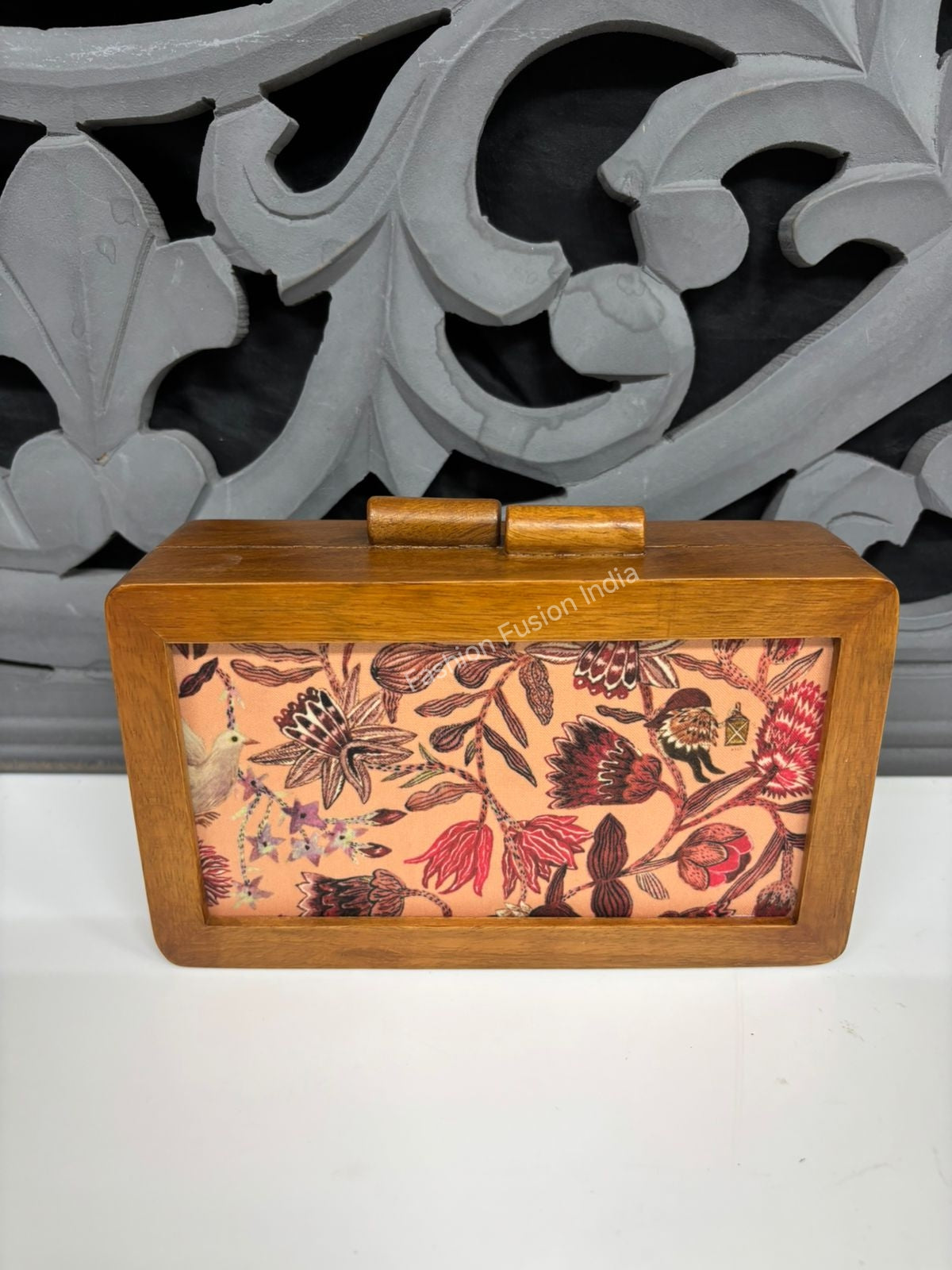 Elegant floral wooden clutch bag with bird artwork on warm beige background.