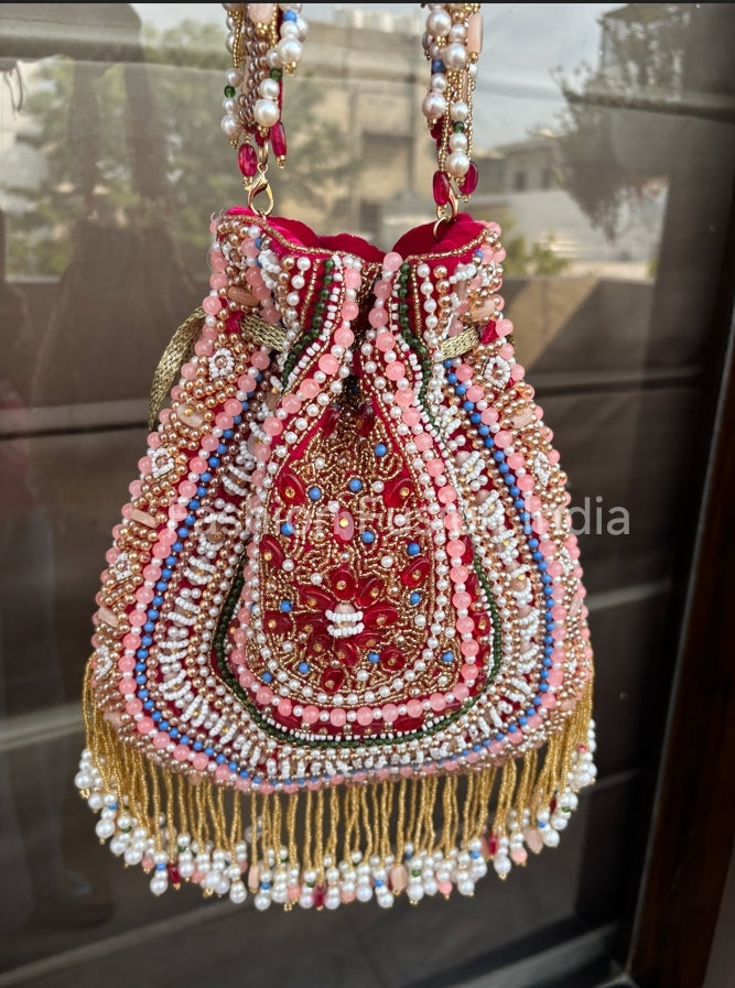 Decorative handbag with intricate beadwork and embroidery on a reflective surface.