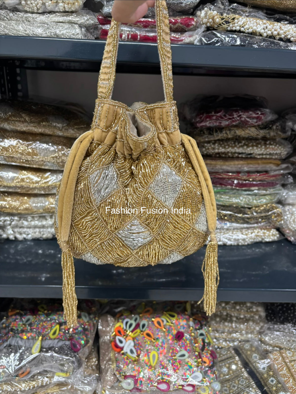 Gold beaded handbag with 'Fashion Fusion India' branding on a blurred background of similar products.