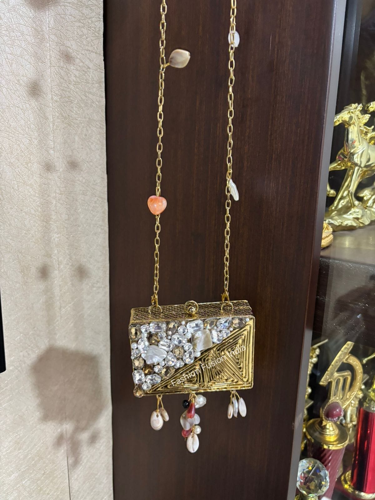 Gold jewelry box with decorative chain and beads on a wooden surface