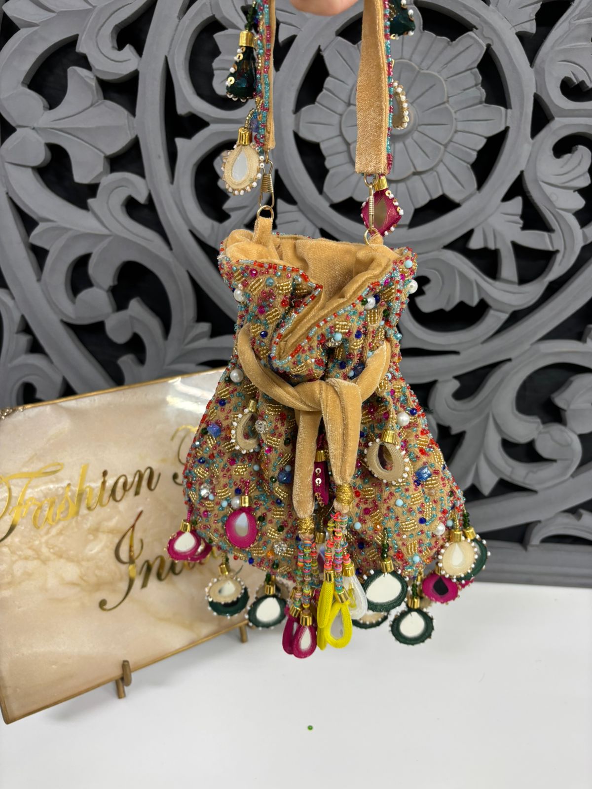 Colorful beaded handbag with decorative elements on a white surface with 'Fashion Inn' sign.