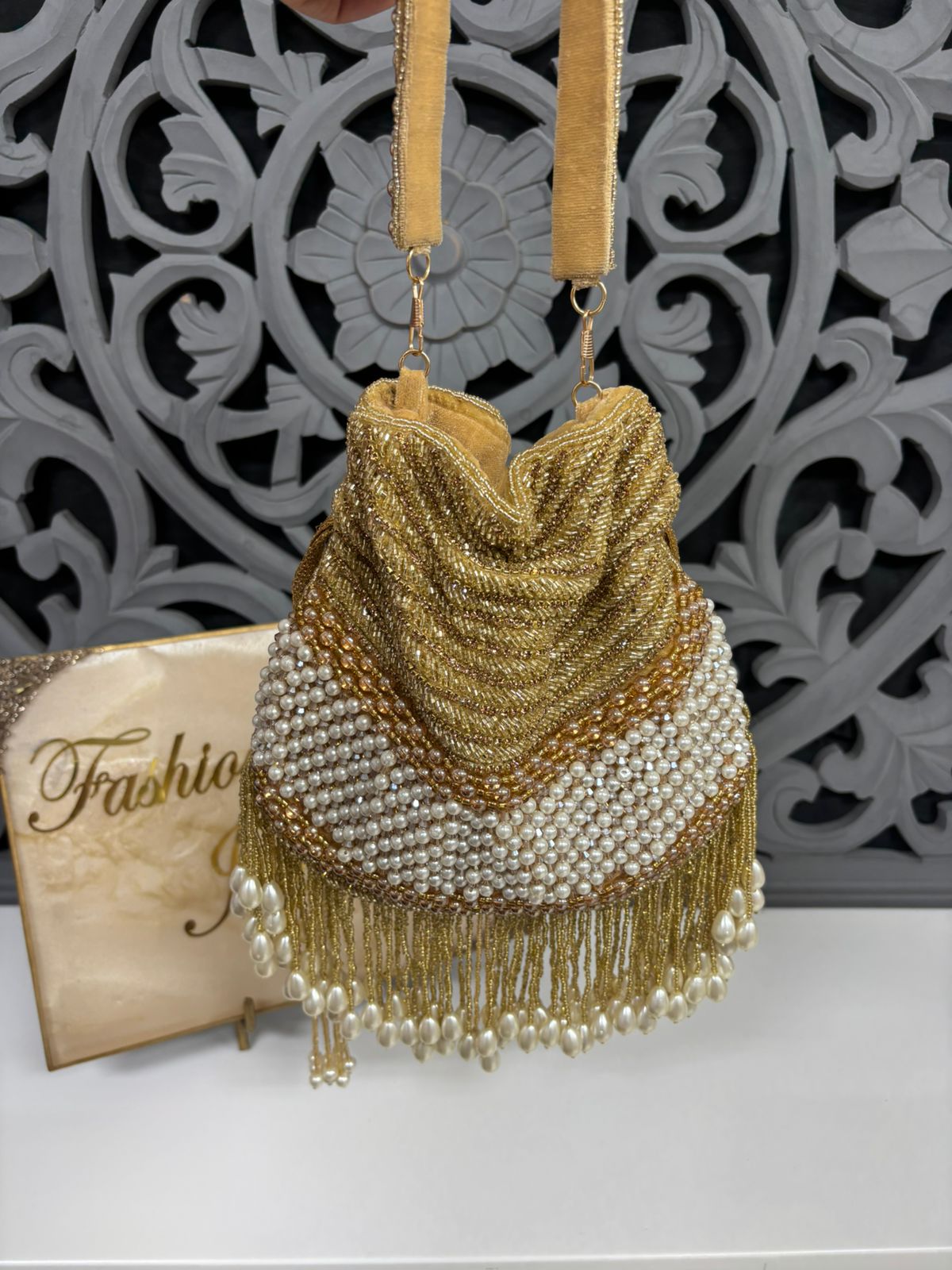 Gold beaded handbag with tassels on a decorative background