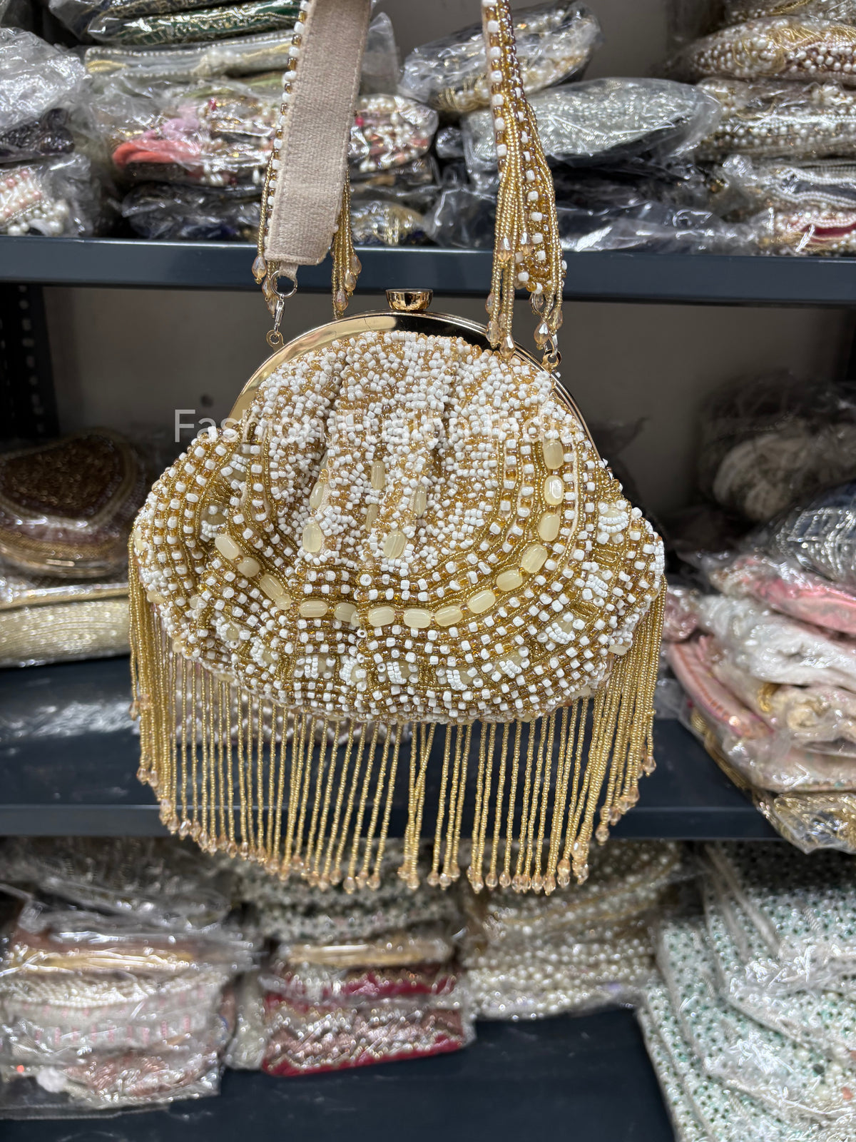Gold beaded handbag with tassels on a shelf with similar bags in the background