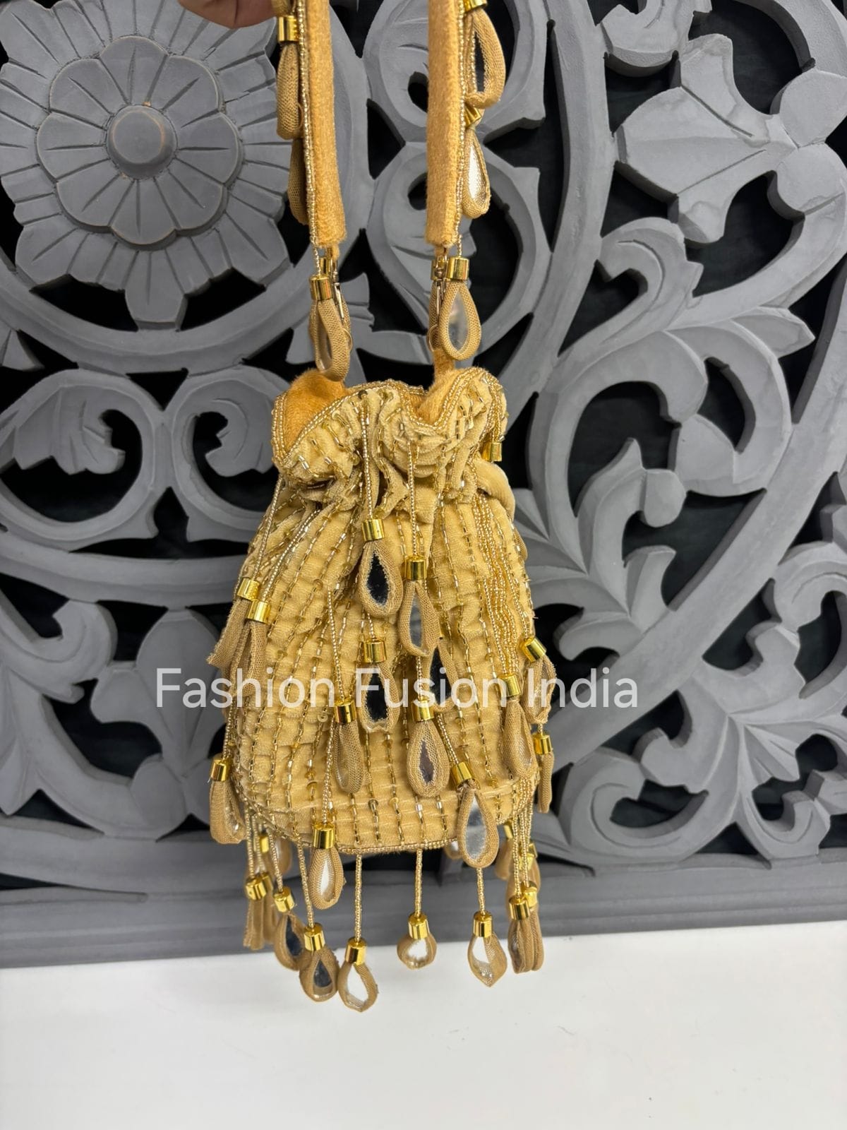 Gold drawstring bag with decorative elements against a decorative gray background