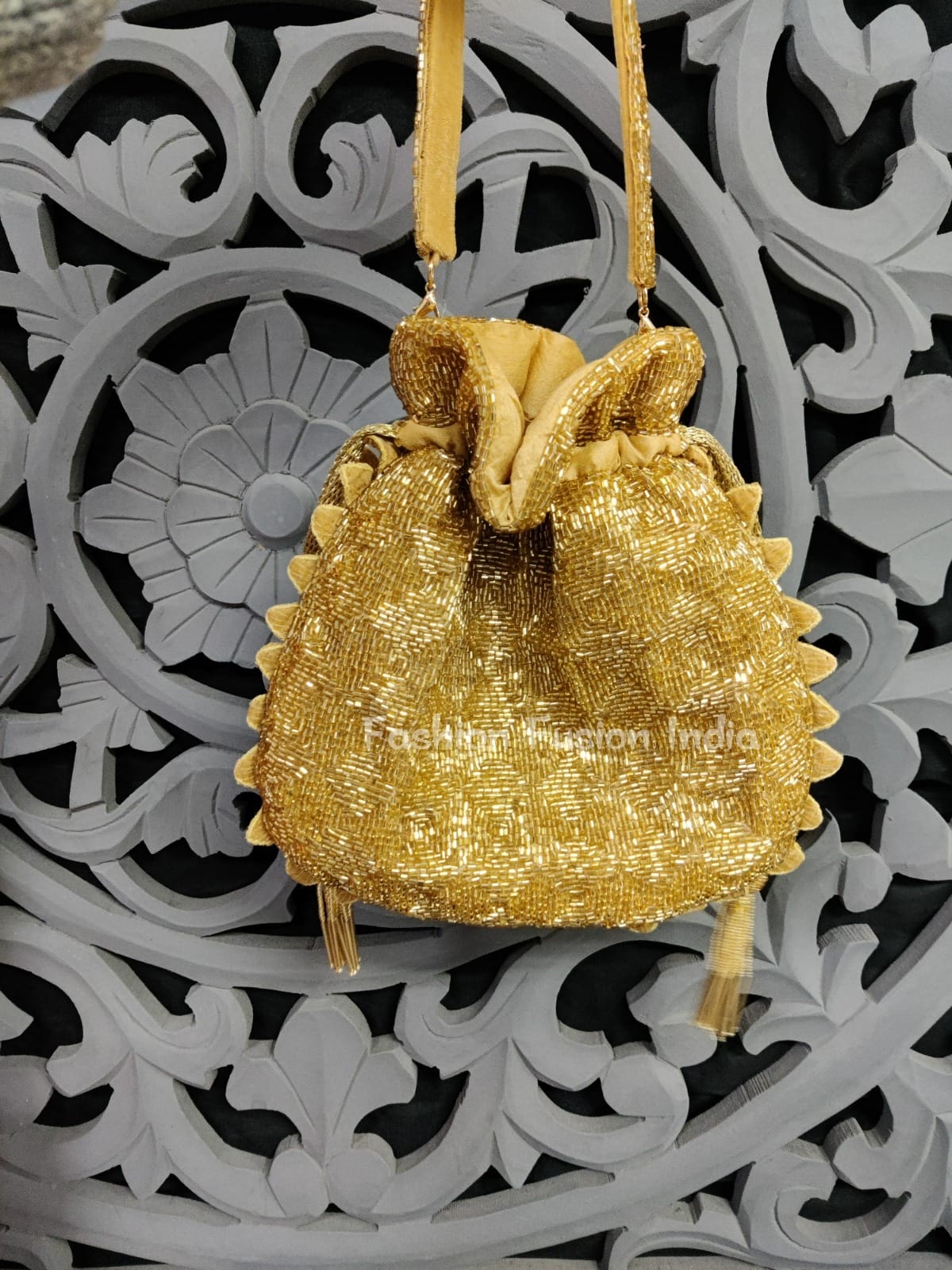 Gold beaded handbag hanging against a decorative black and white background
