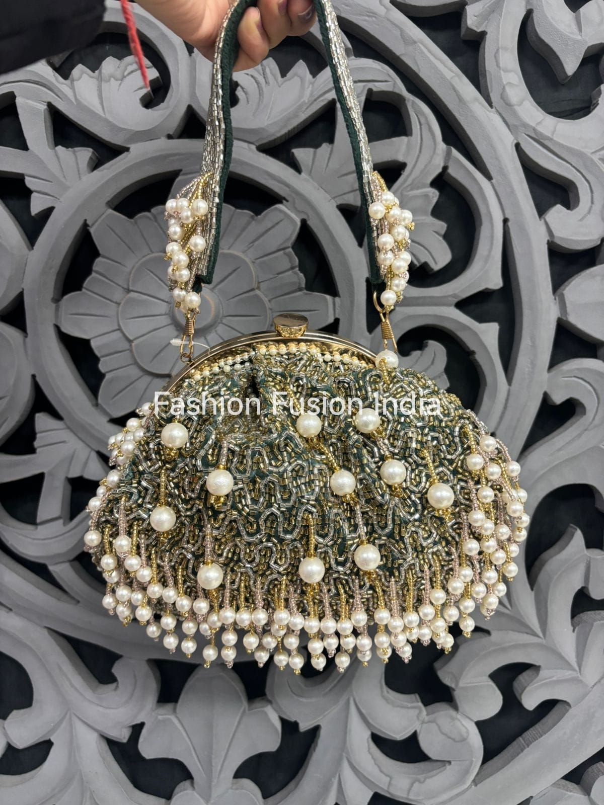 Decorative handbag with pearl details held against an ornate background