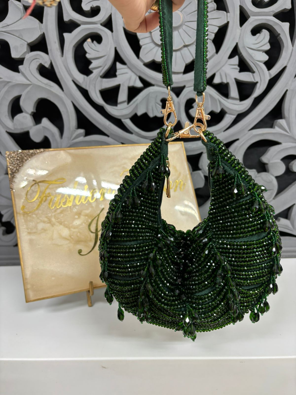 Green beaded handbag with gold accents on a decorative background