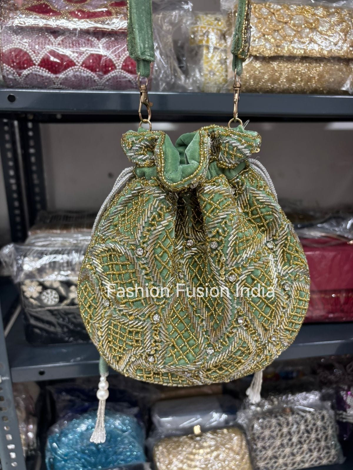 Green embroidered handbag with 'Fashion Fusion India' branding on a blurred background of other bags.