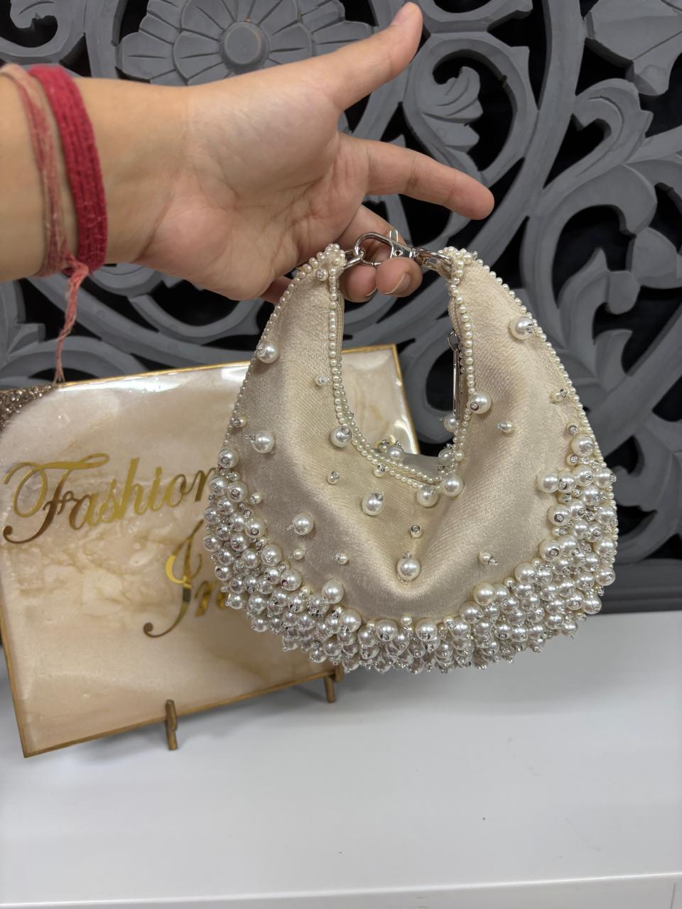 Hand holding a beaded handbag with a decorative background