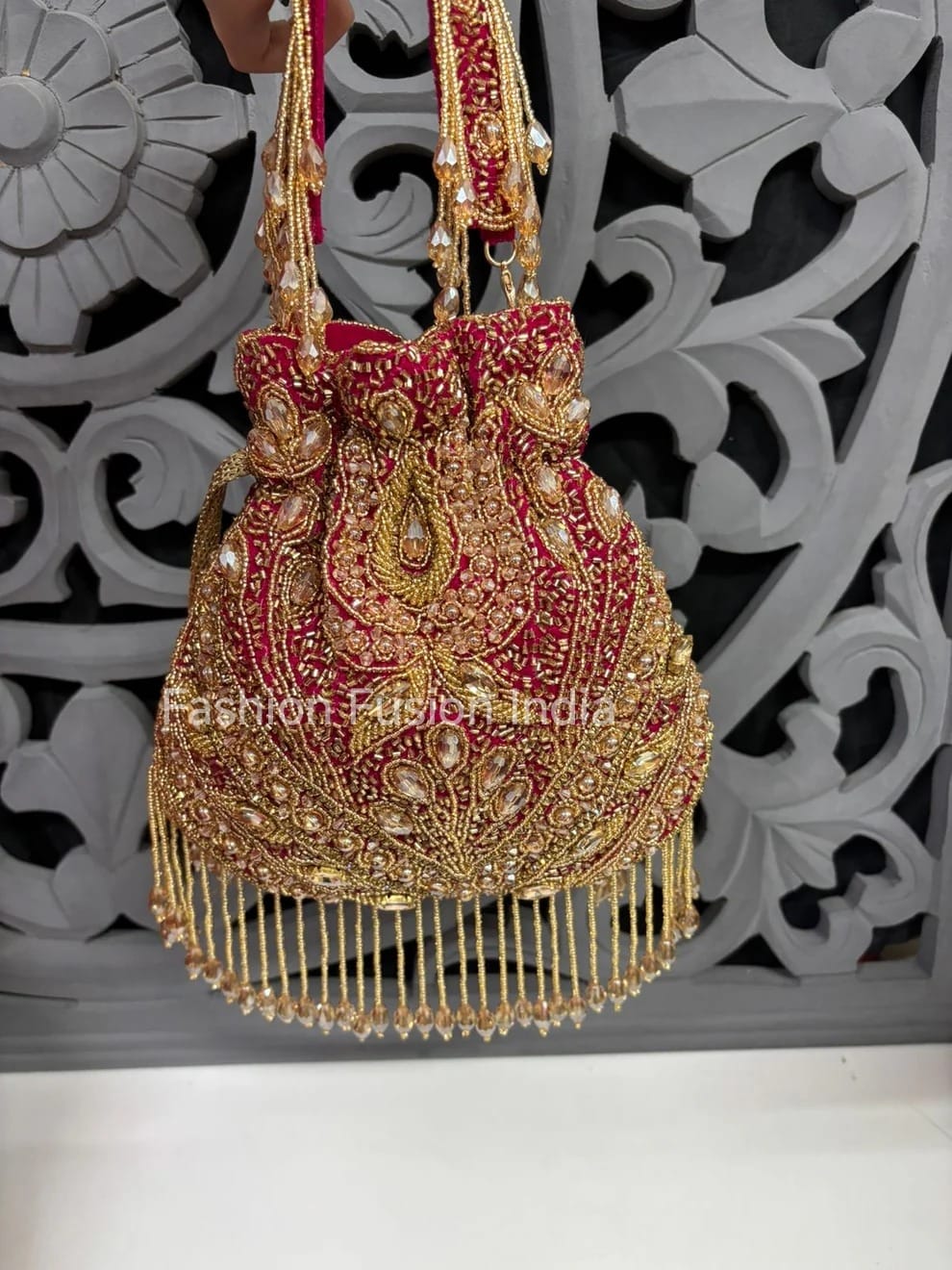 Decorative handbag with gold embroidery and red fabric against a decorative wall.