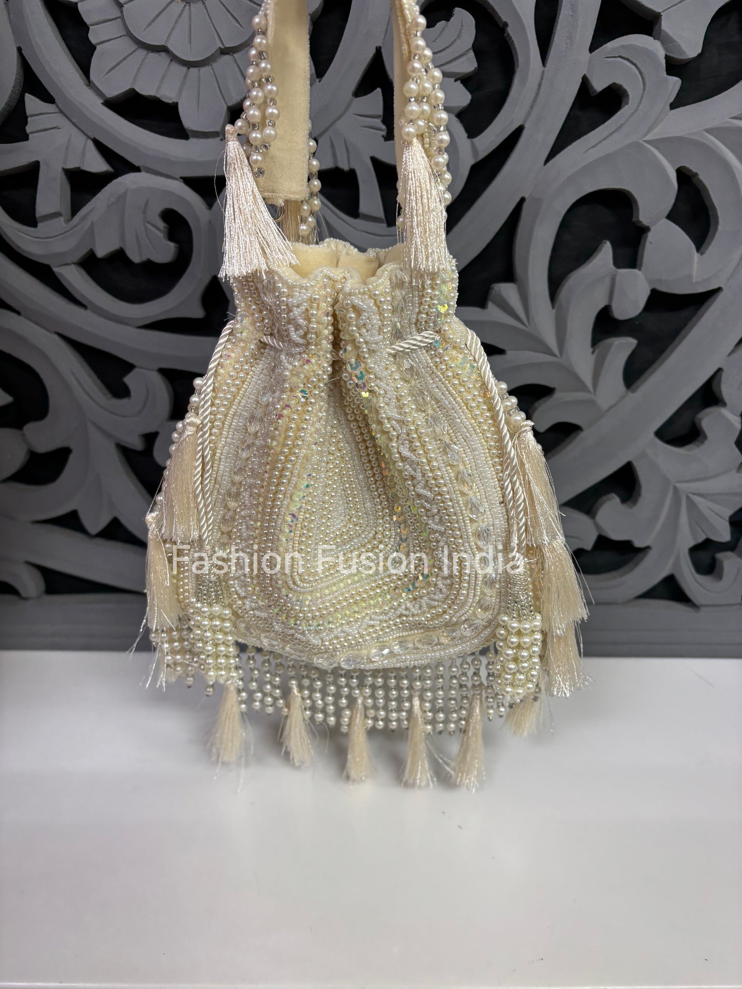 Beaded handbag with tassels on a decorative background, labeled 'Fashion Fusion India'.
