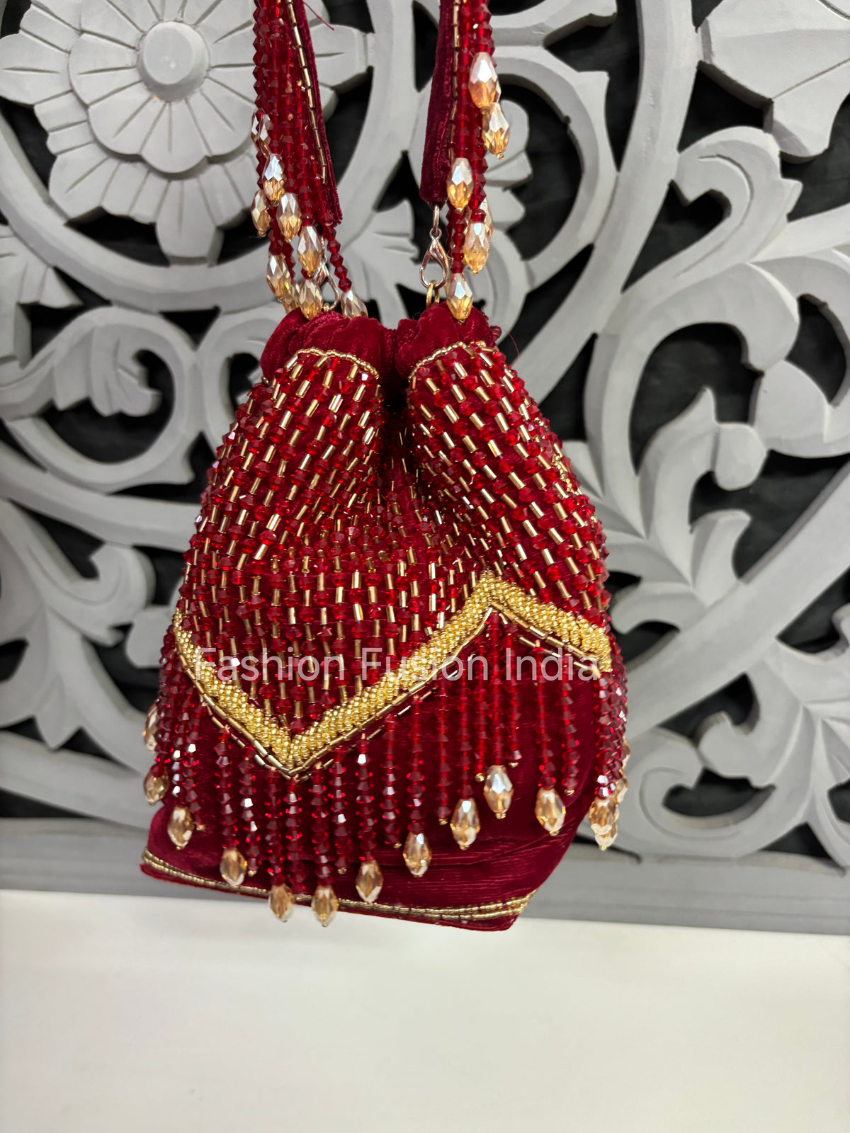 Red and gold beaded handbag with intricate design on a decorative white background