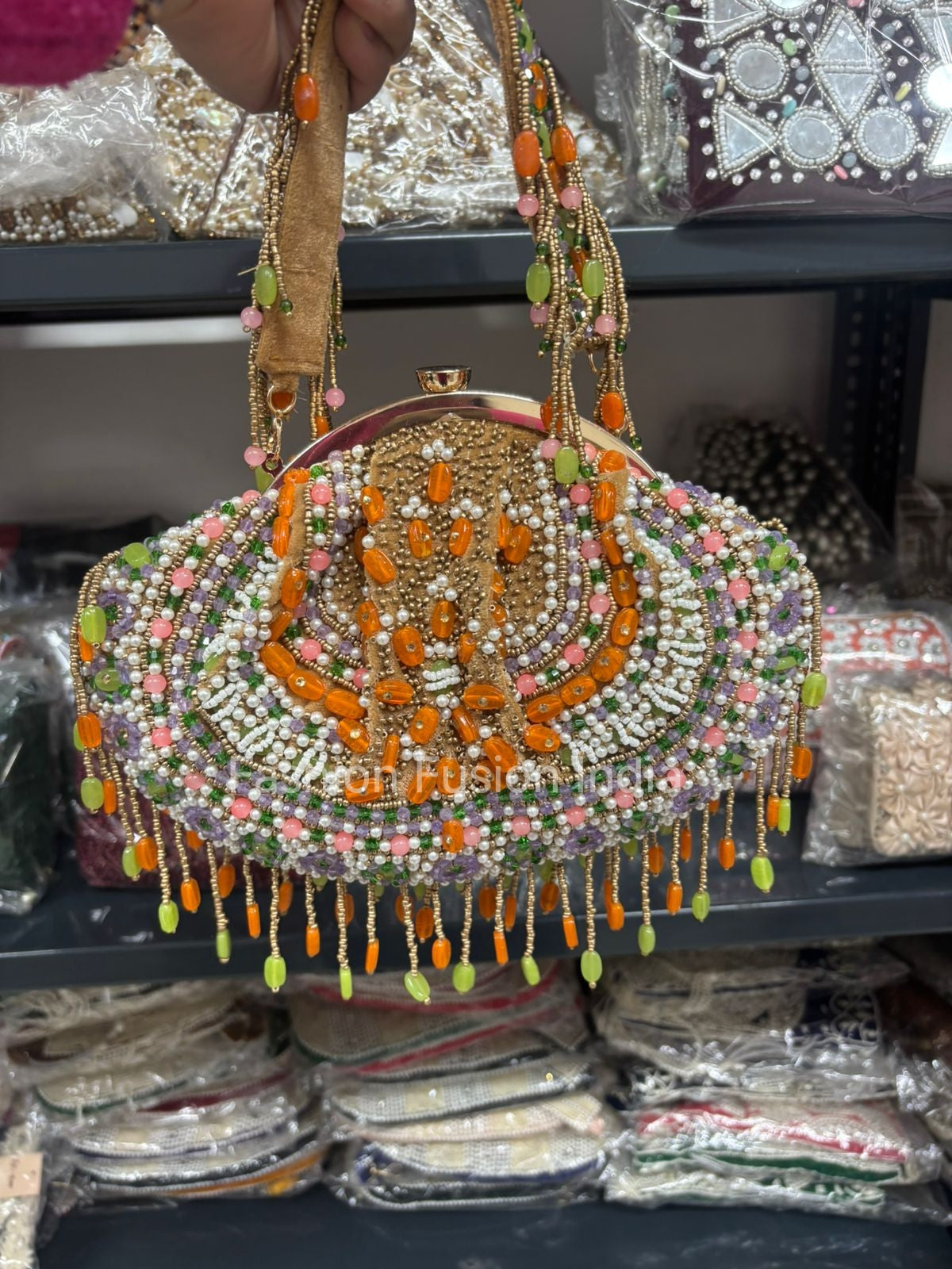 Decorative handbag with beads and tassels held by a person, with a blurred background of similar items.