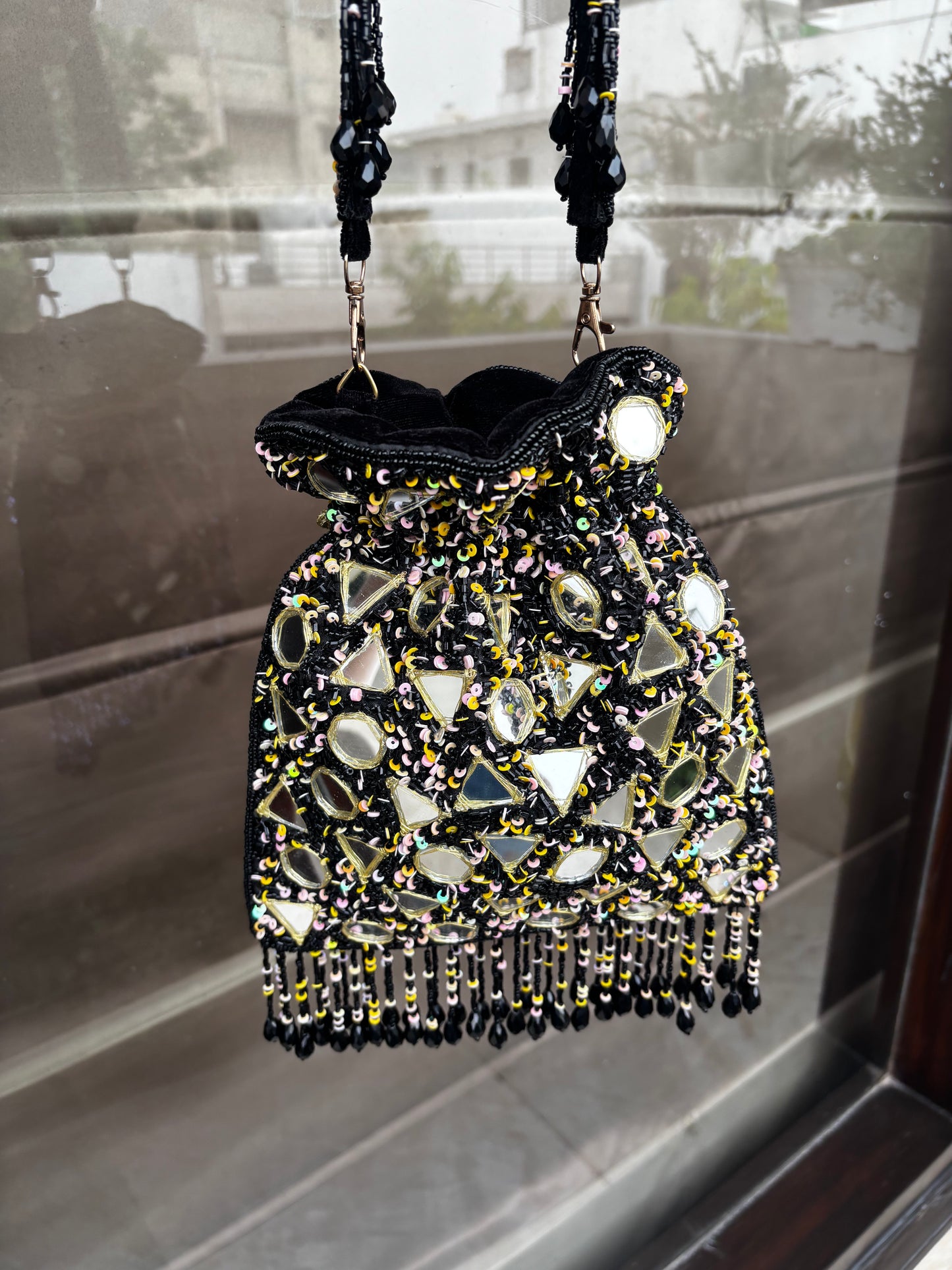Beaded handbag with black strap on a reflective surface