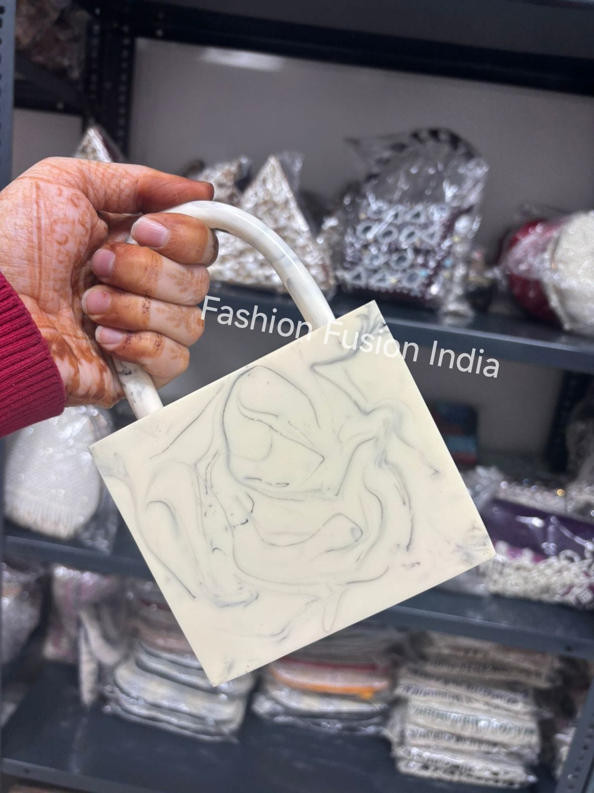 Hand holding a small white bag with a pattern against a blurred background