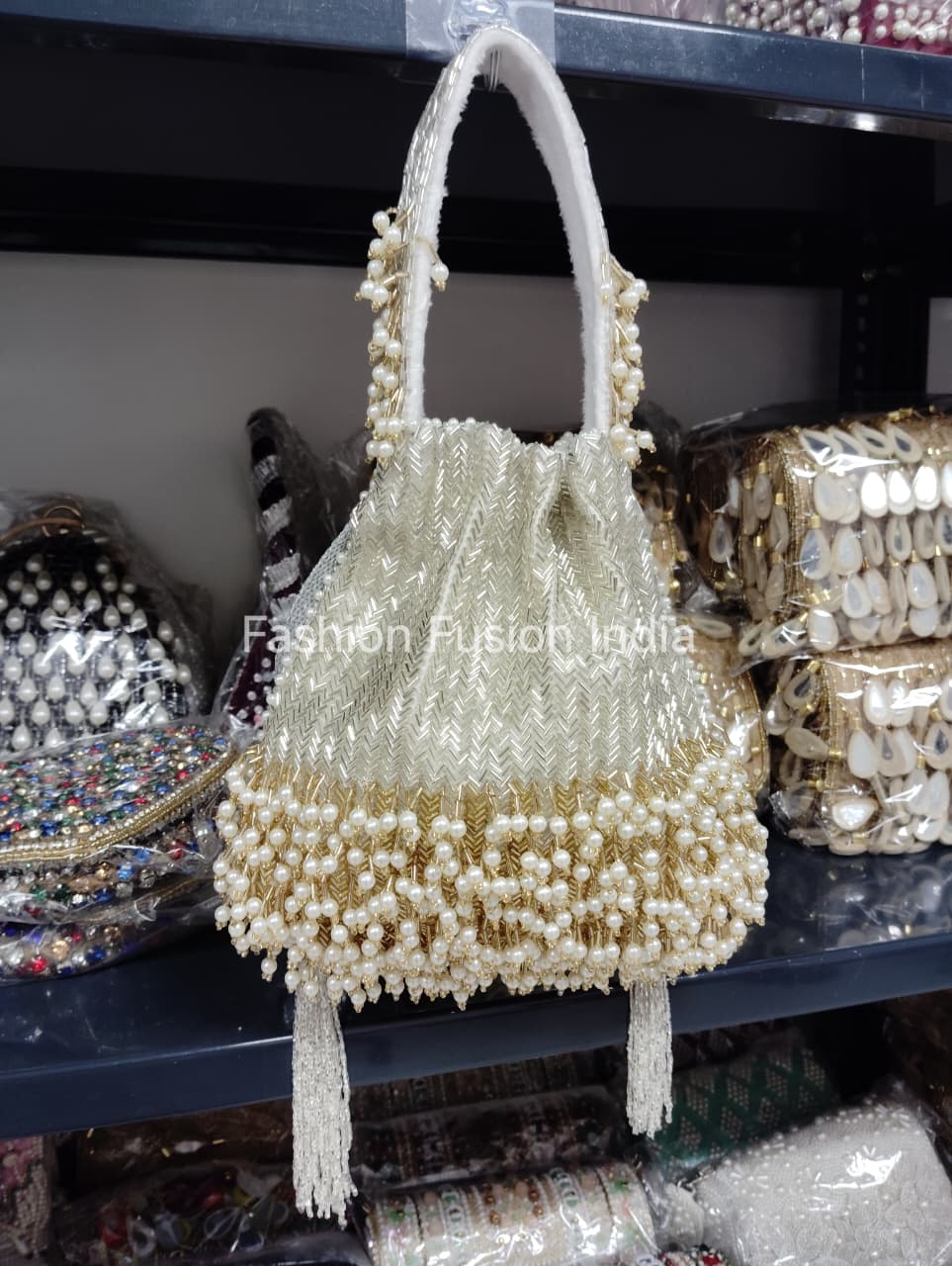 Beaded handbag with tassels on a shelf with other bags in the background.