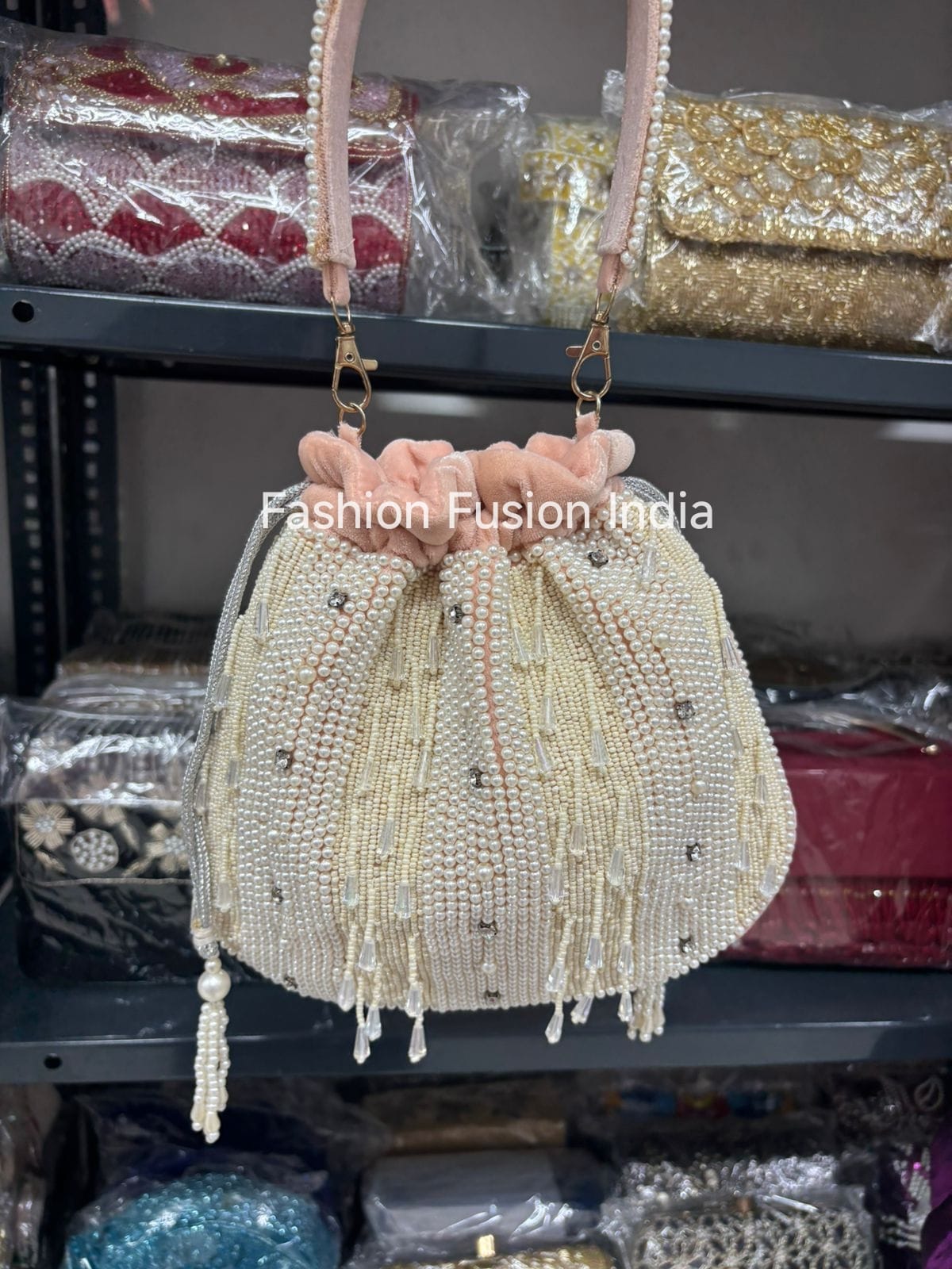 Beaded handbag with pink top handle on a shelf with other bags.