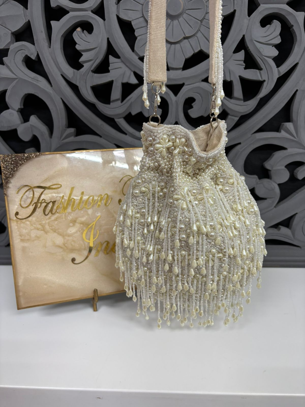Ivory pearl potli bag with beadwork and fringe tassels, ideal for bridal wear.