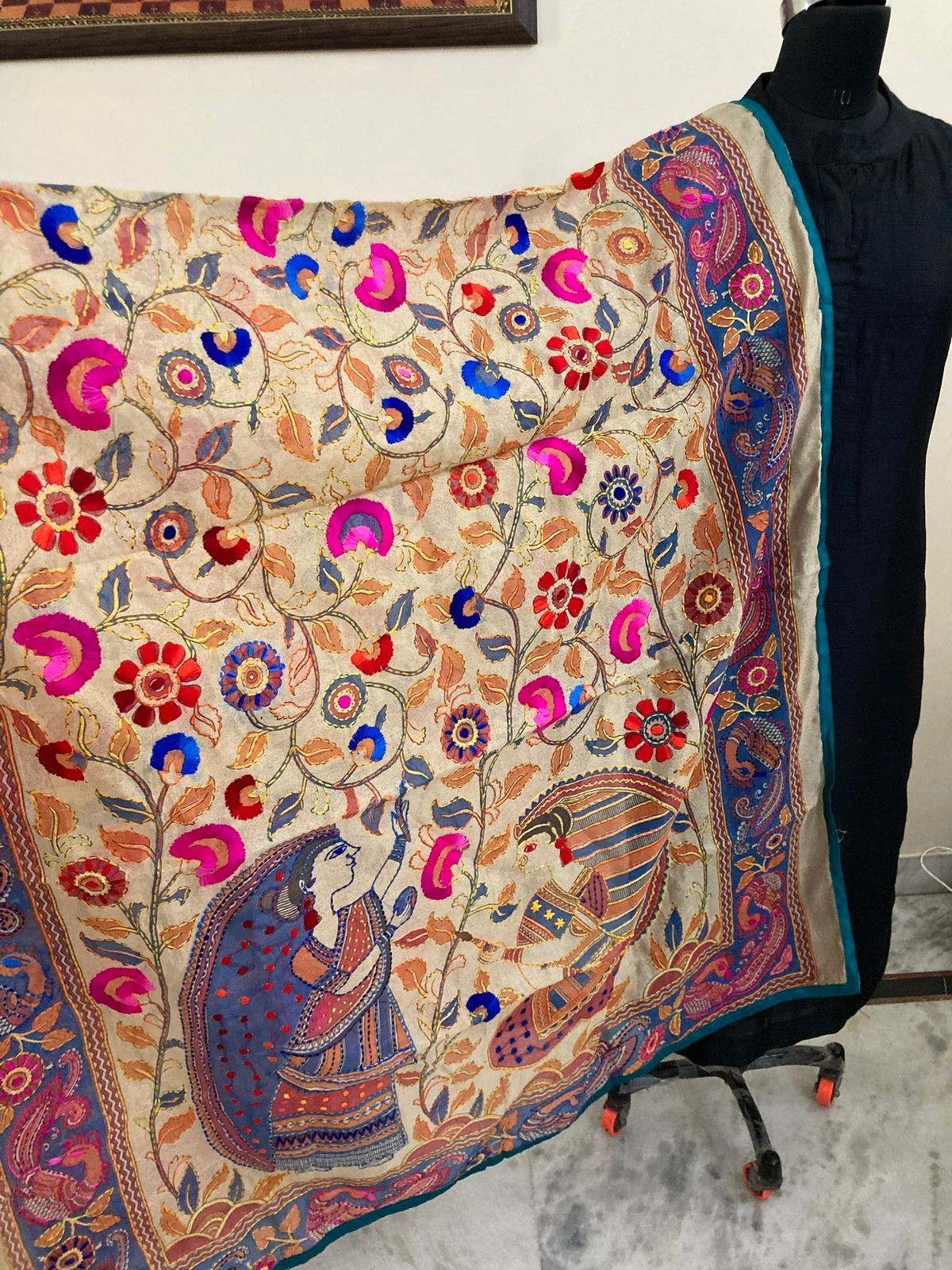 Colorful embroidered fabric on a mannequin against a neutral background