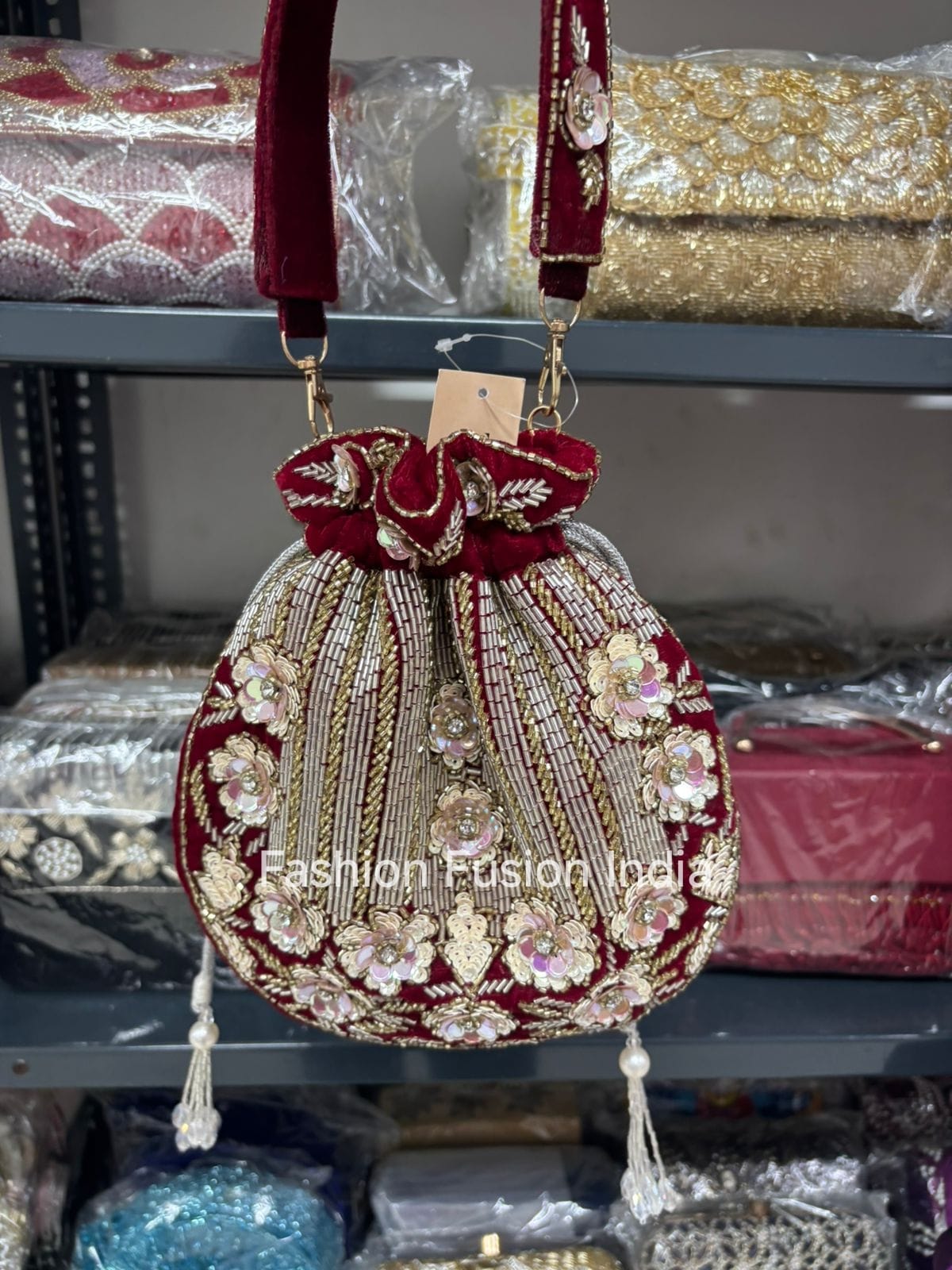 Decorative handbag with floral patterns and red accents on a shelf with wrapped items.