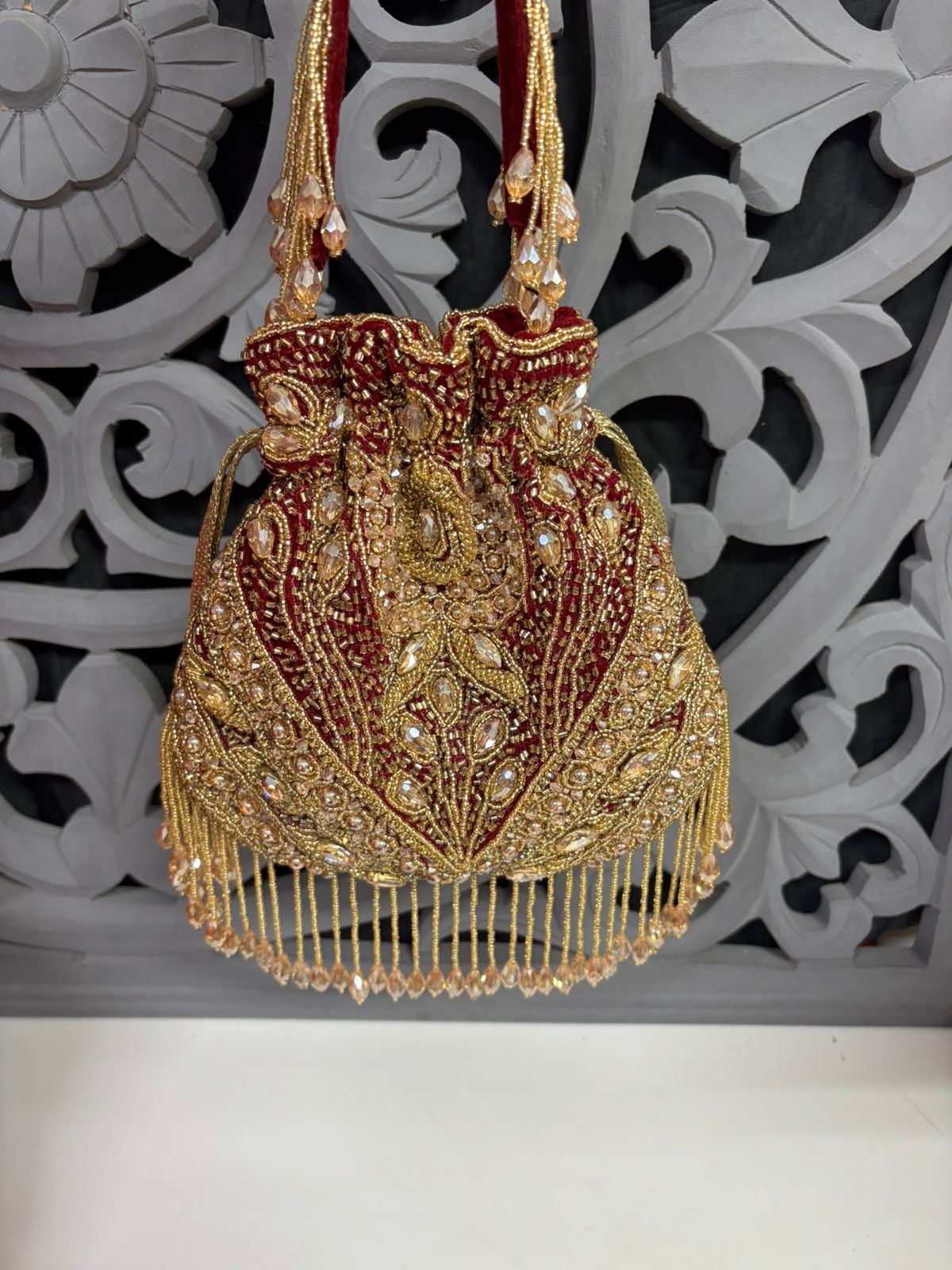Decorative handbag with gold and red details against a decorative white background