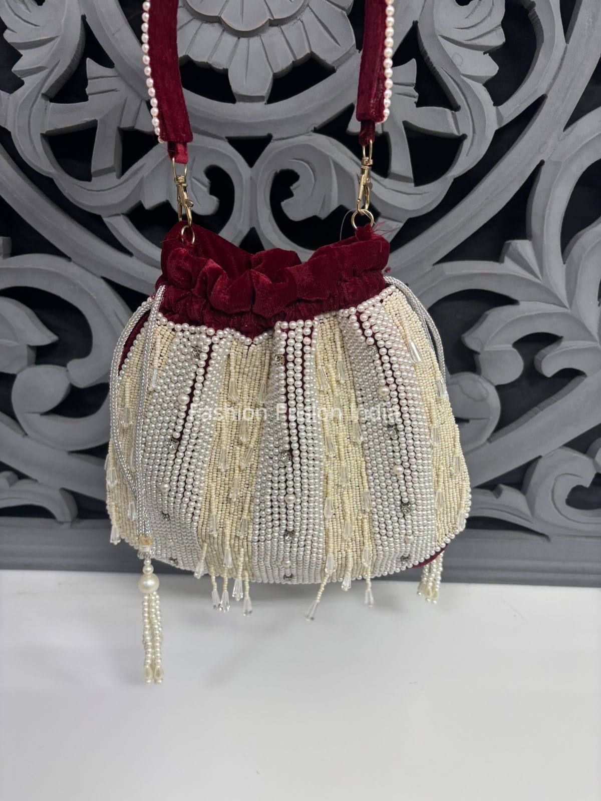 Decorative handbag with beaded details and red velvet top against a decorative wall.