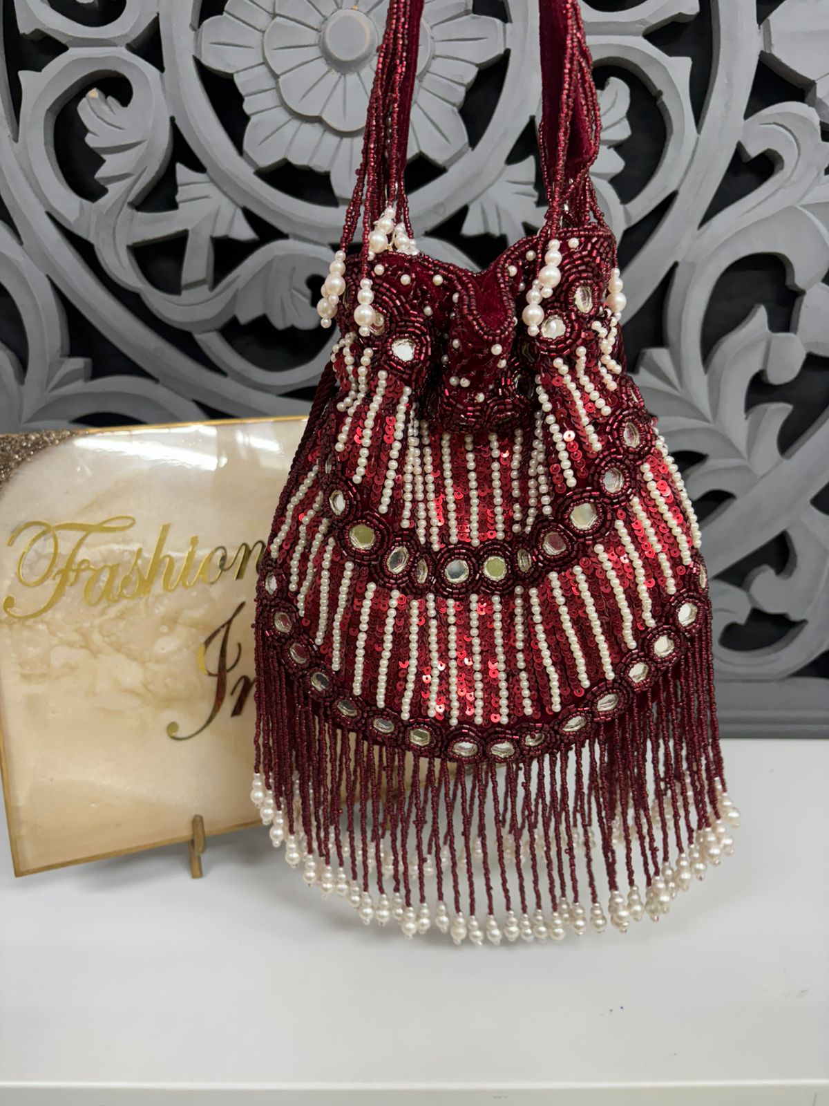 Beaded handbag with fringes and pearls on a decorative background