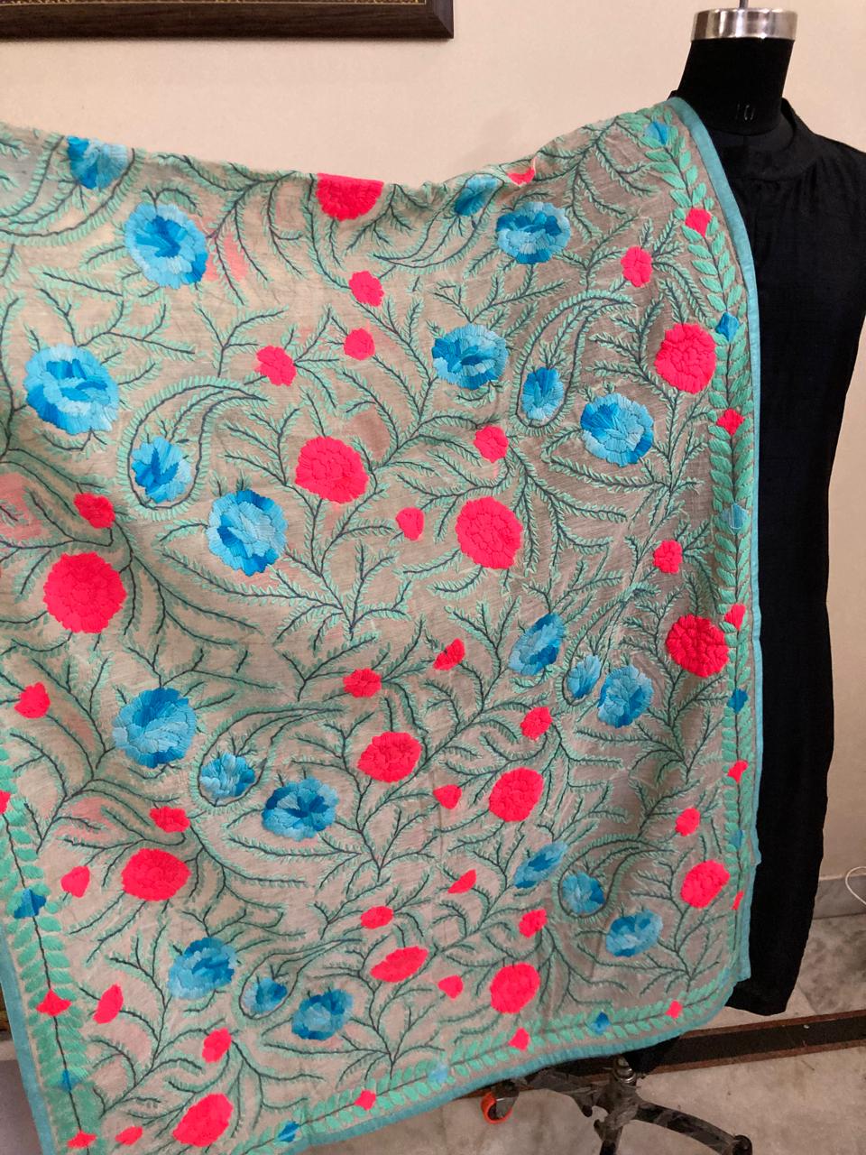 Embroidered fabric with floral patterns on a mannequin against a beige background