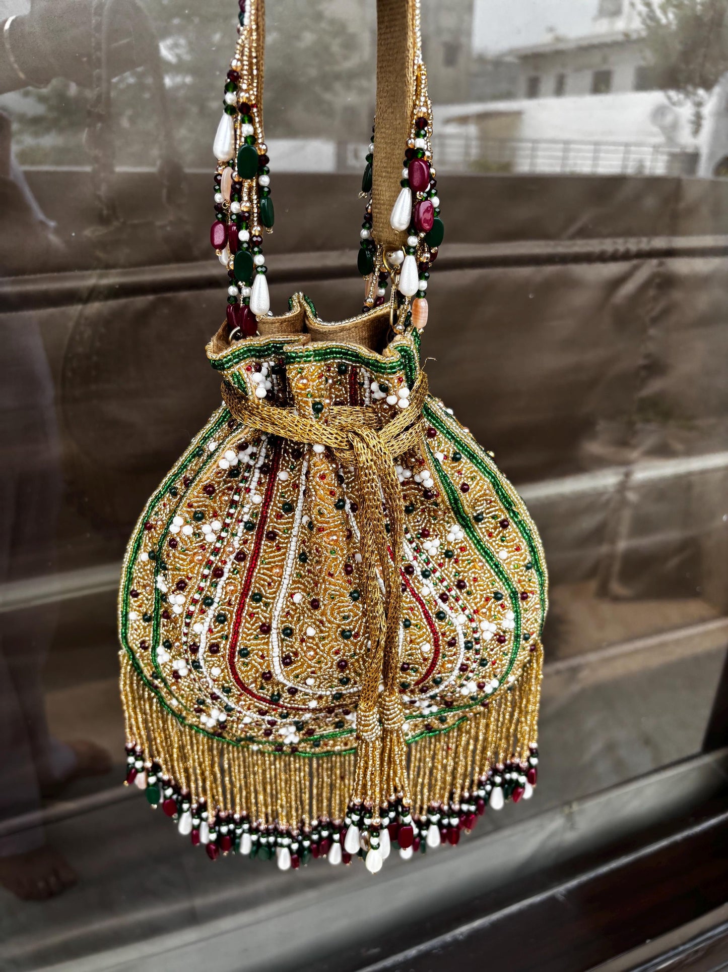 Decorative handbag with gold embroidery and beads on a reflective surface