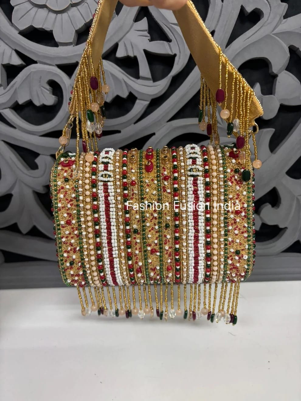 Decorative handbag with beaded and embroidered details on a white surface with a decorative background.