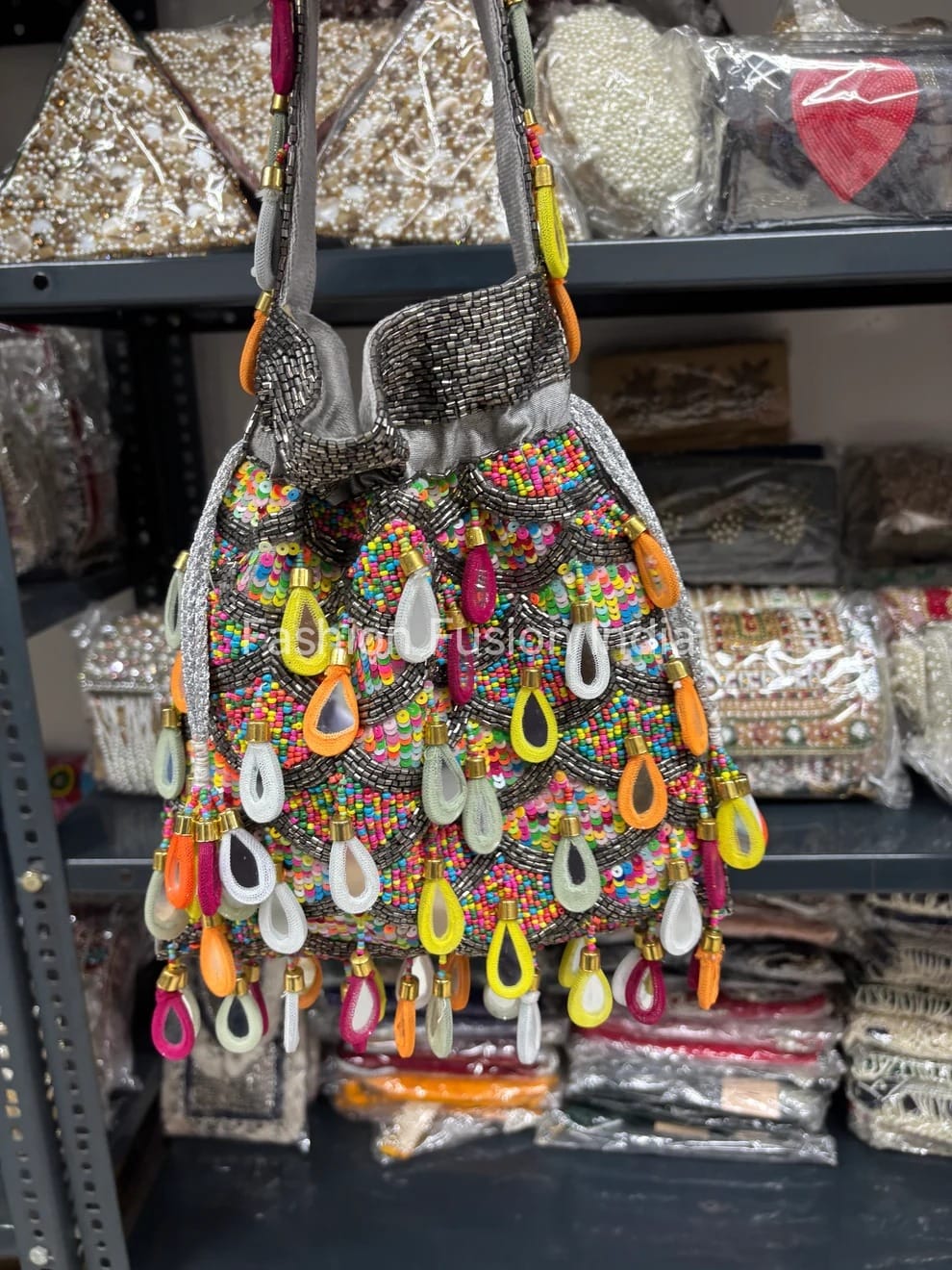 Colorful beaded handbag with decorative elements on a shelf with similar items.