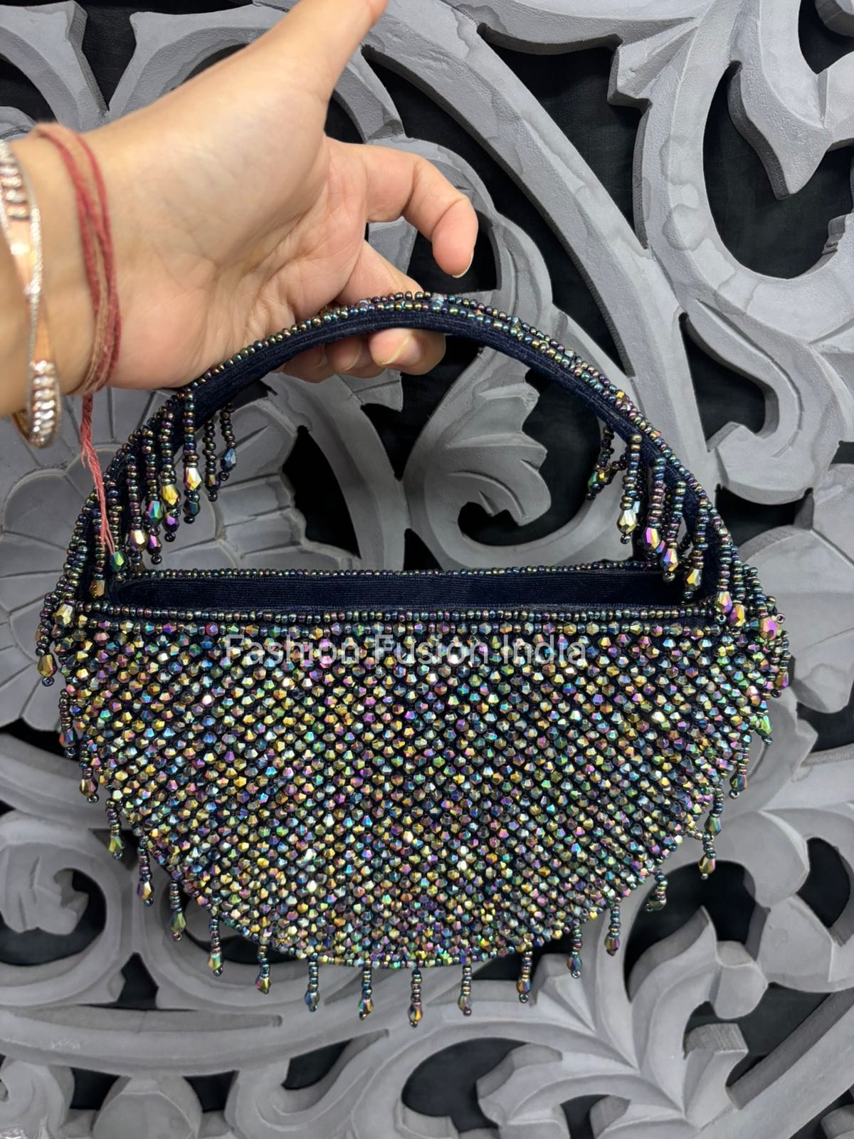 Hand holding a beaded handbag against an ornate decorative background