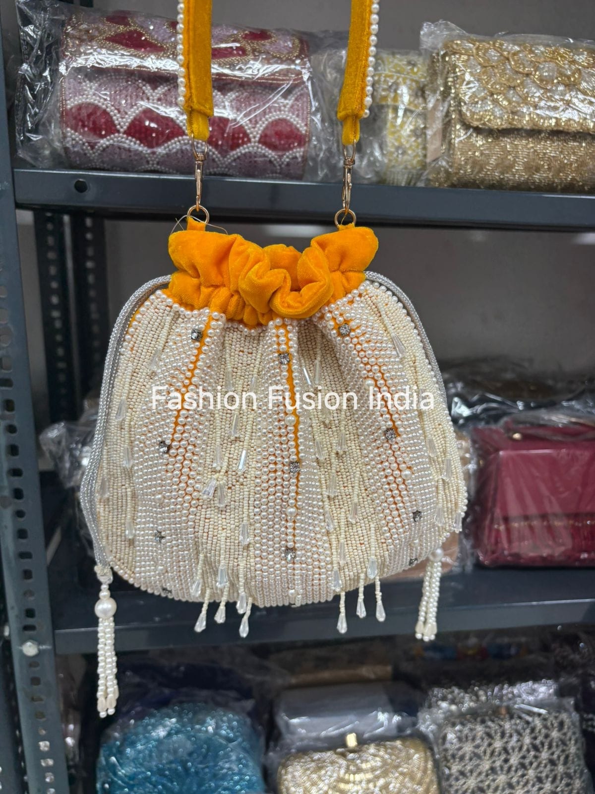 Decorative handbag with yellow top and beaded details on a shelf with other bags.
