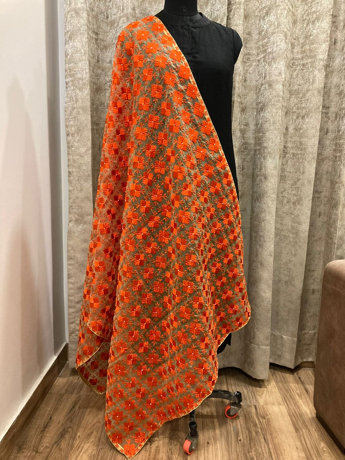 Orange floral patterned fabric draped over a mannequin against a neutral background