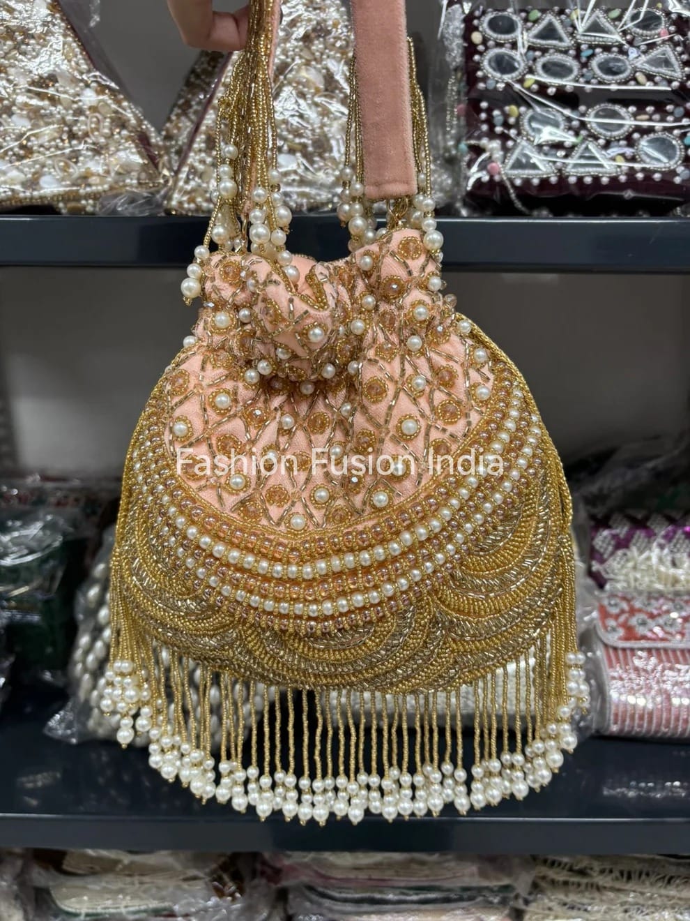 Decorative handbag with gold embroidery and pearl details, held by a person.