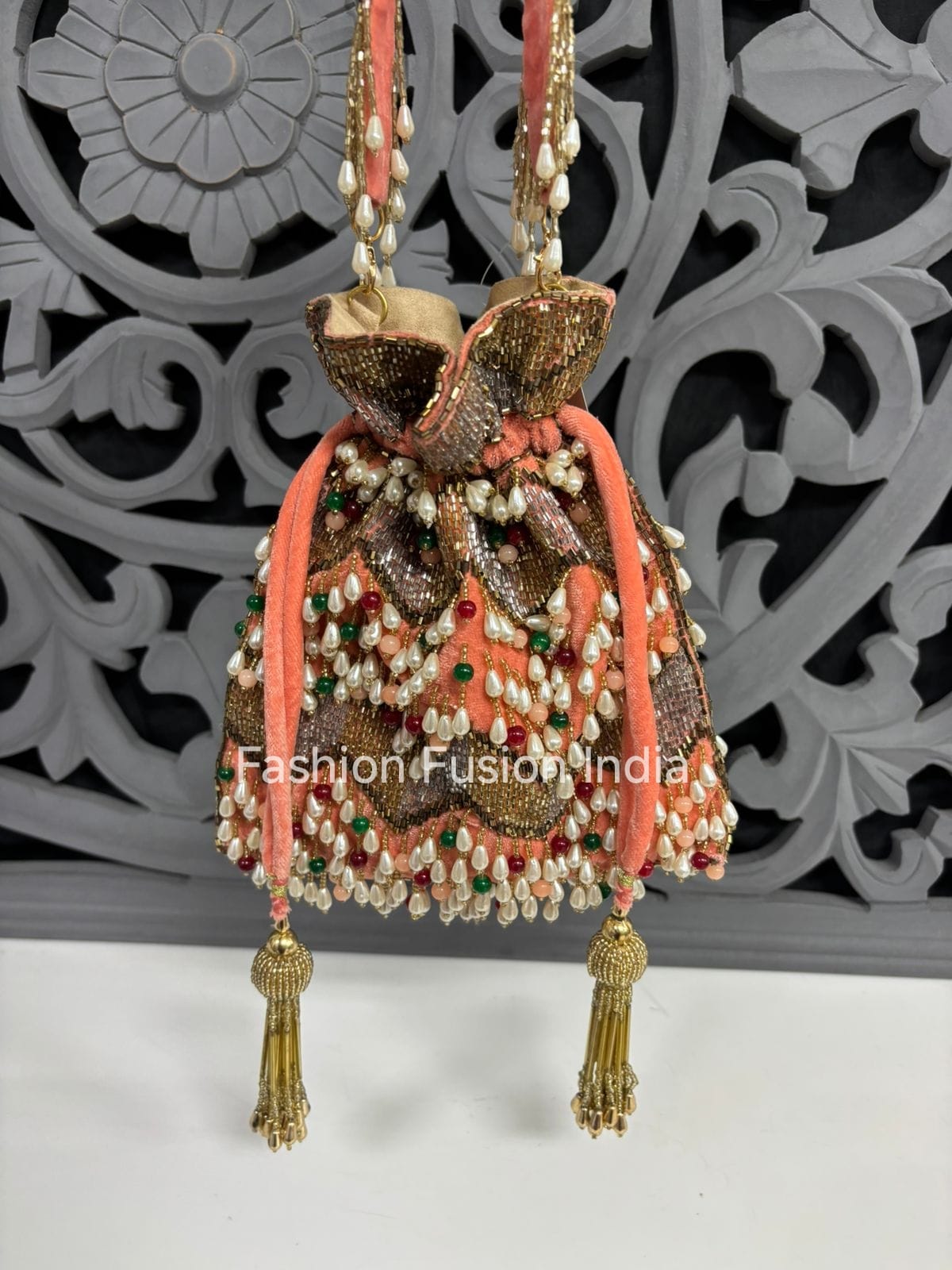 Decorative handbag with intricate designs and tassels against a decorative wall.