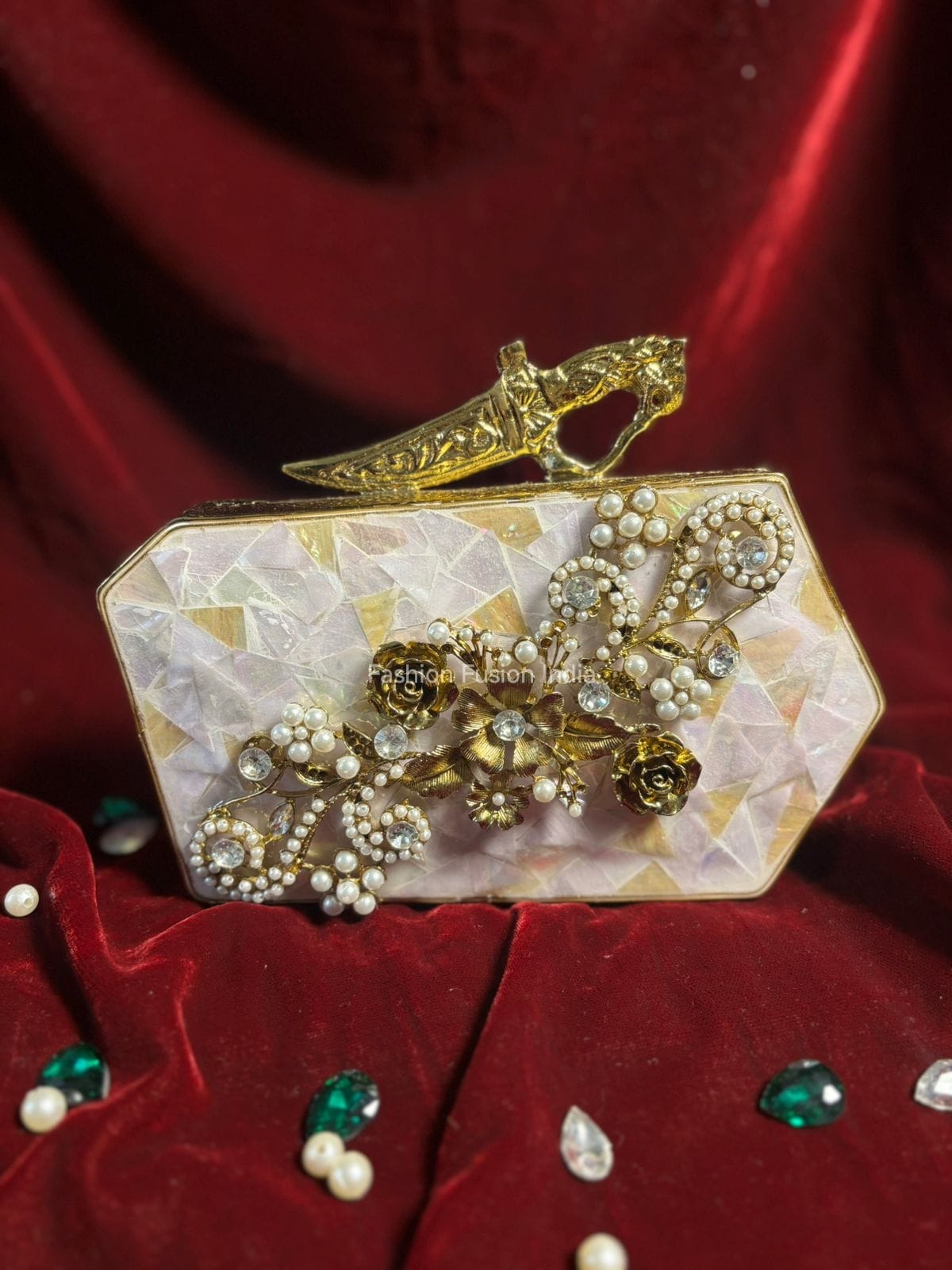 Decorative clutch with gold accents and pearls on a red fabric background